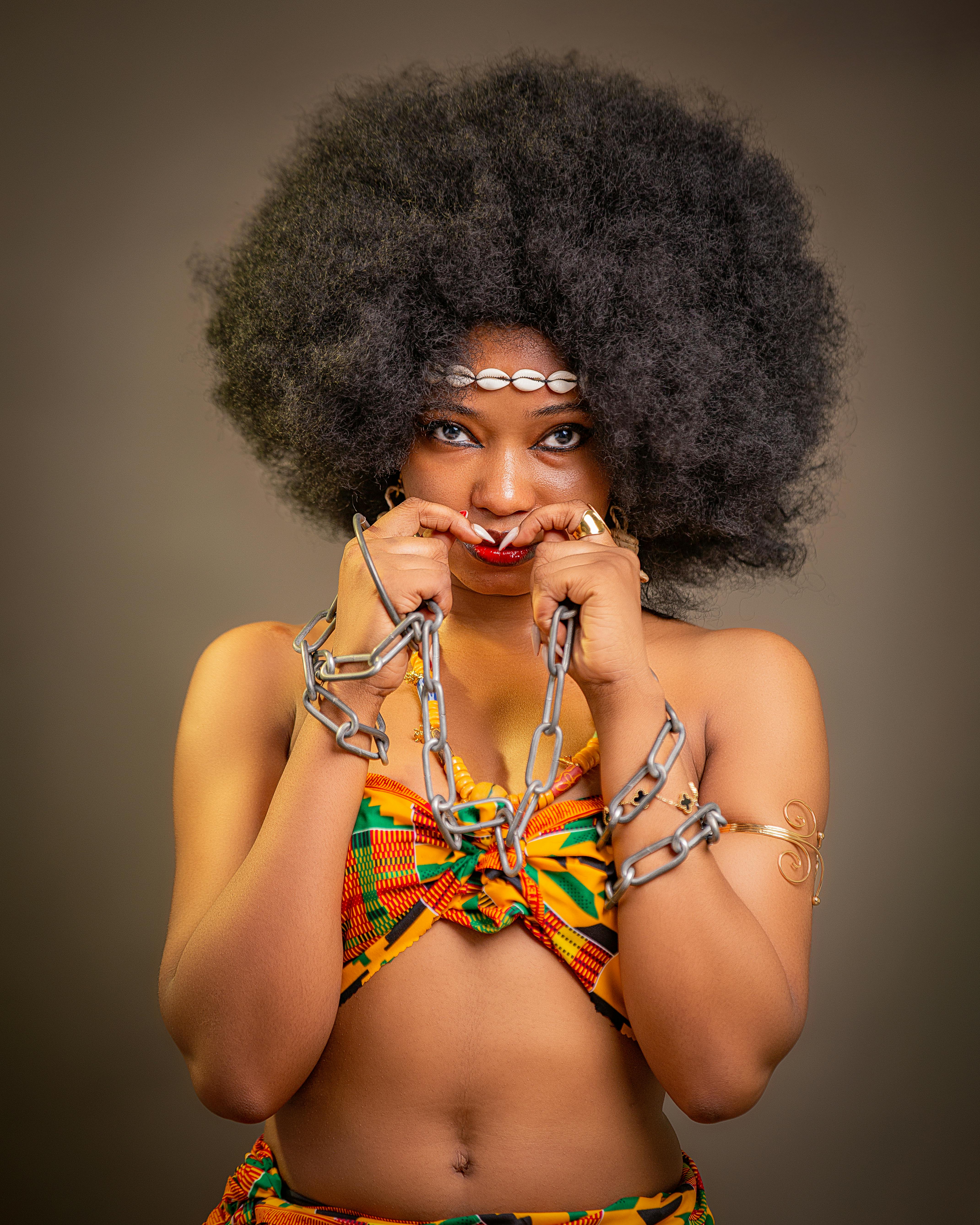 免費 一幅藝術肖像畫，描繪了一位身著色彩鮮豔的肯特布、佩戴鏈條的加納女性，展現了文化表達。 圖庫相片