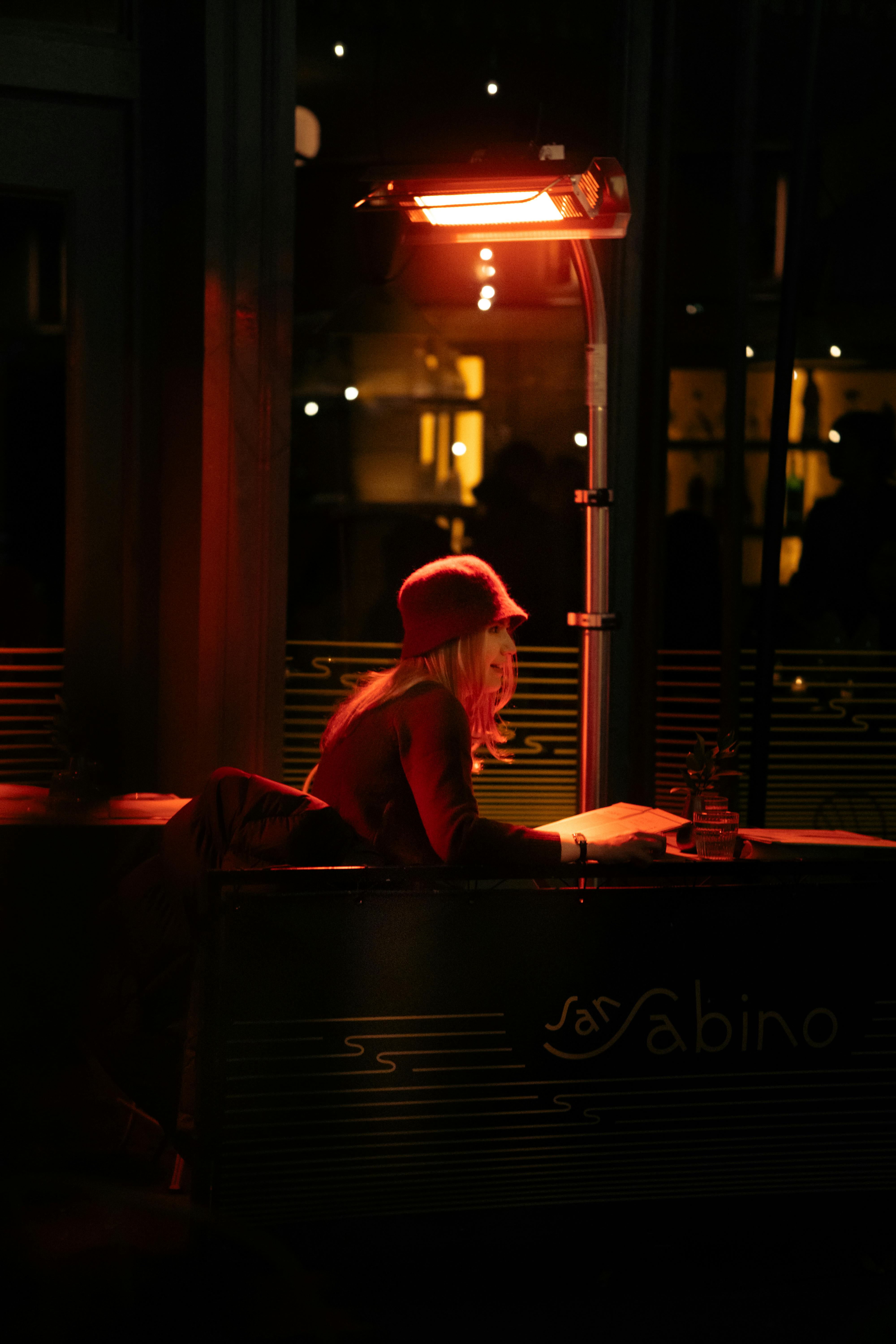 Безкоштовне Жінка сидить і читає під вуличним обігрівачем у вуличному кафе в Нью-Йорку. стокове фото