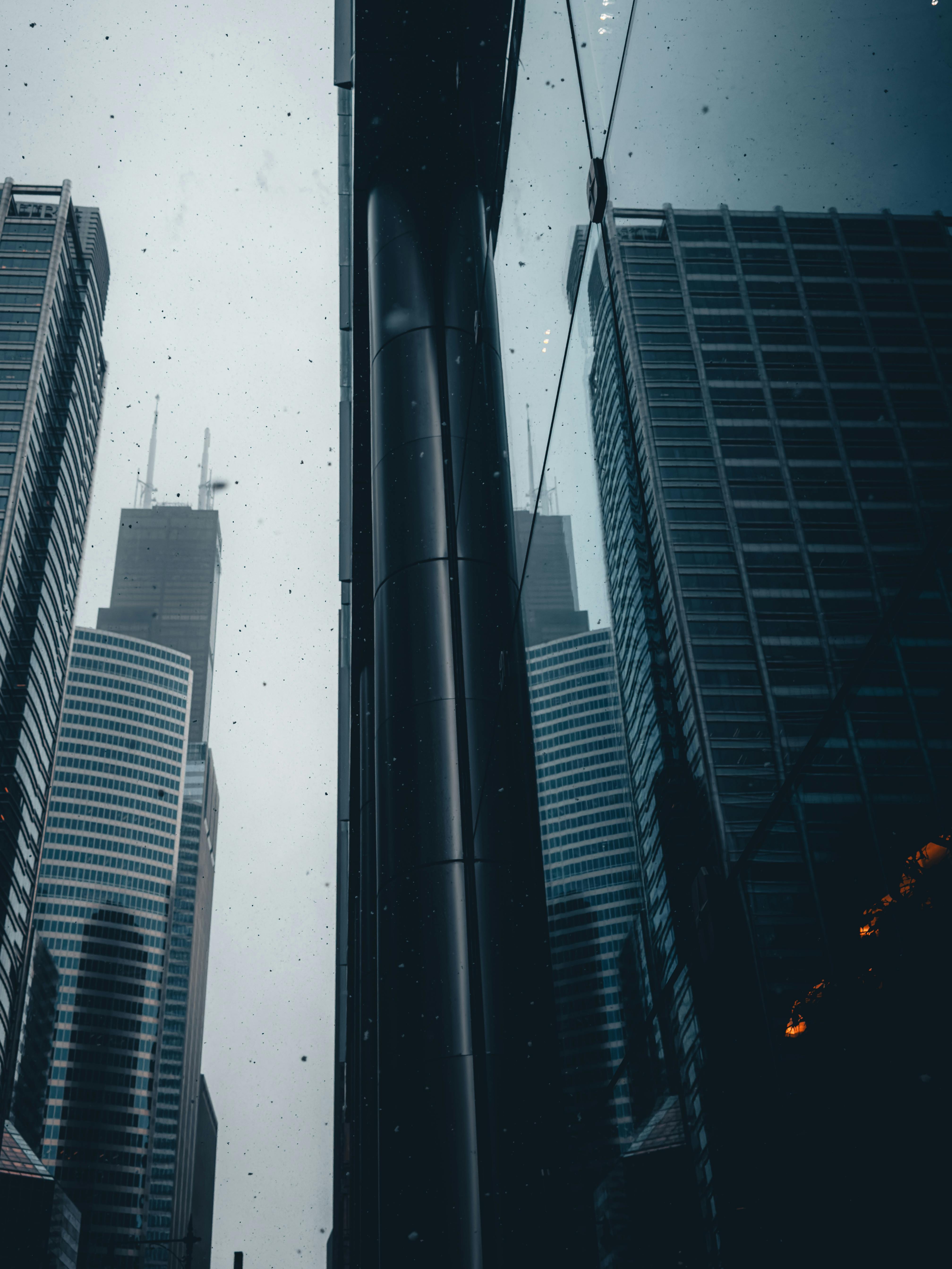 Kostenlos Spektakuläre Aufnahme eines hoch aufragenden Wolkenkratzers mit Spiegelungen auf der Glasfassade an einem bewölkten Tag. Stock-Foto