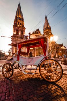 A vintage horse-drawn carriage outside the iconic Guadalajara Cathedral at sunset.