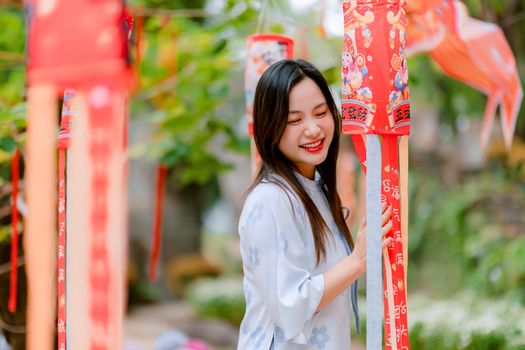 Portrait of a young woman enjoying a vibrant display of red lanterns outdoors.