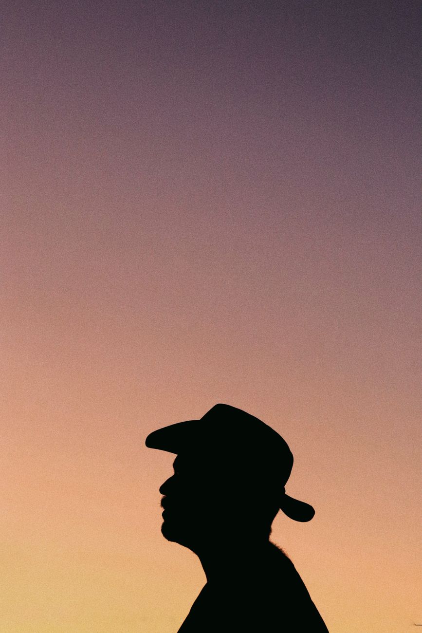 Silhouette of a man wearing a cowboy hat against a colorful sunset sky.. silhouette, wearing, cowboy