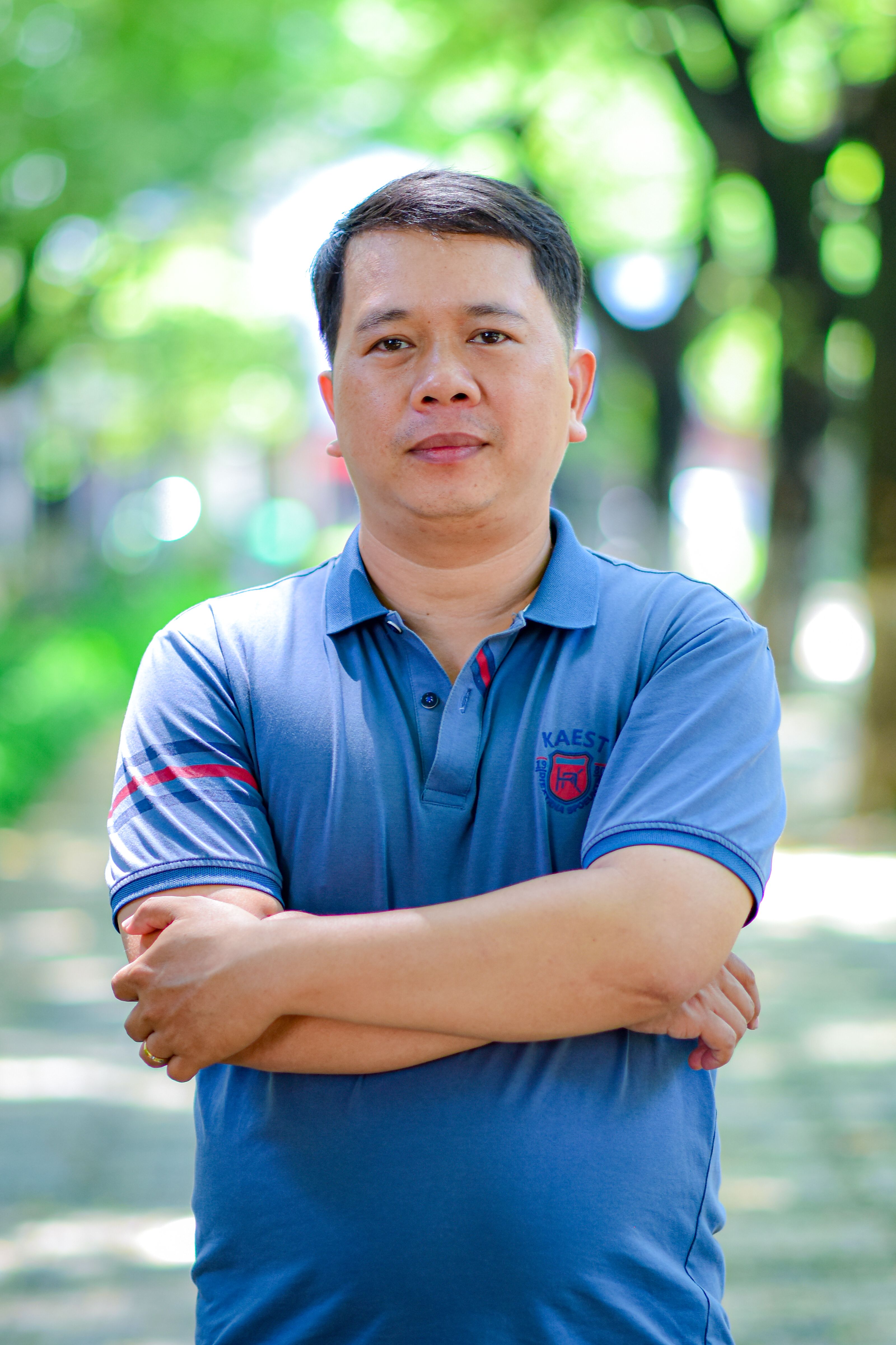 Portrait of a confident man standing outside in a serene green environment.