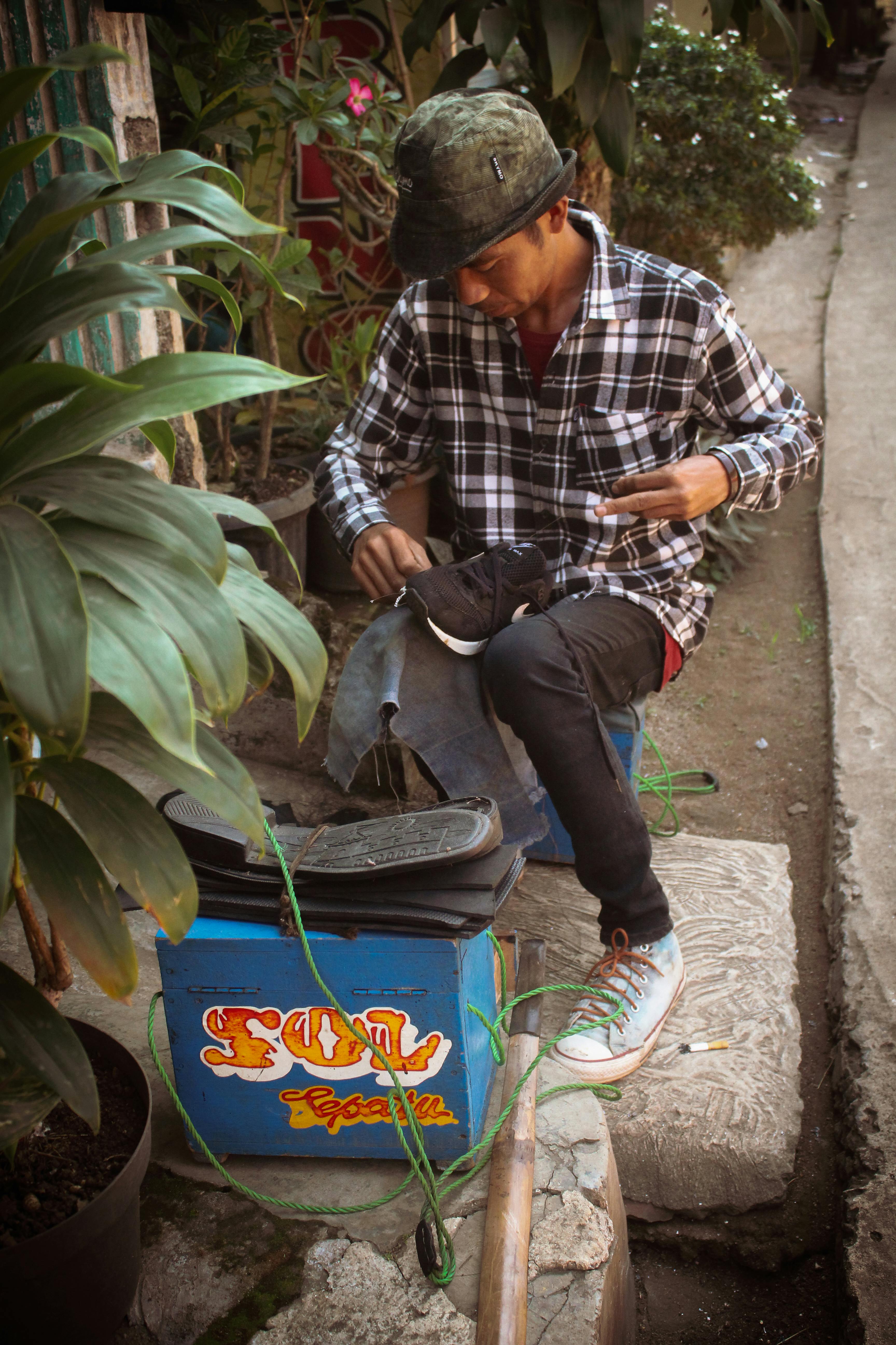 免費 一位年輕男子在街頭攤位修鞋。 圖庫相片