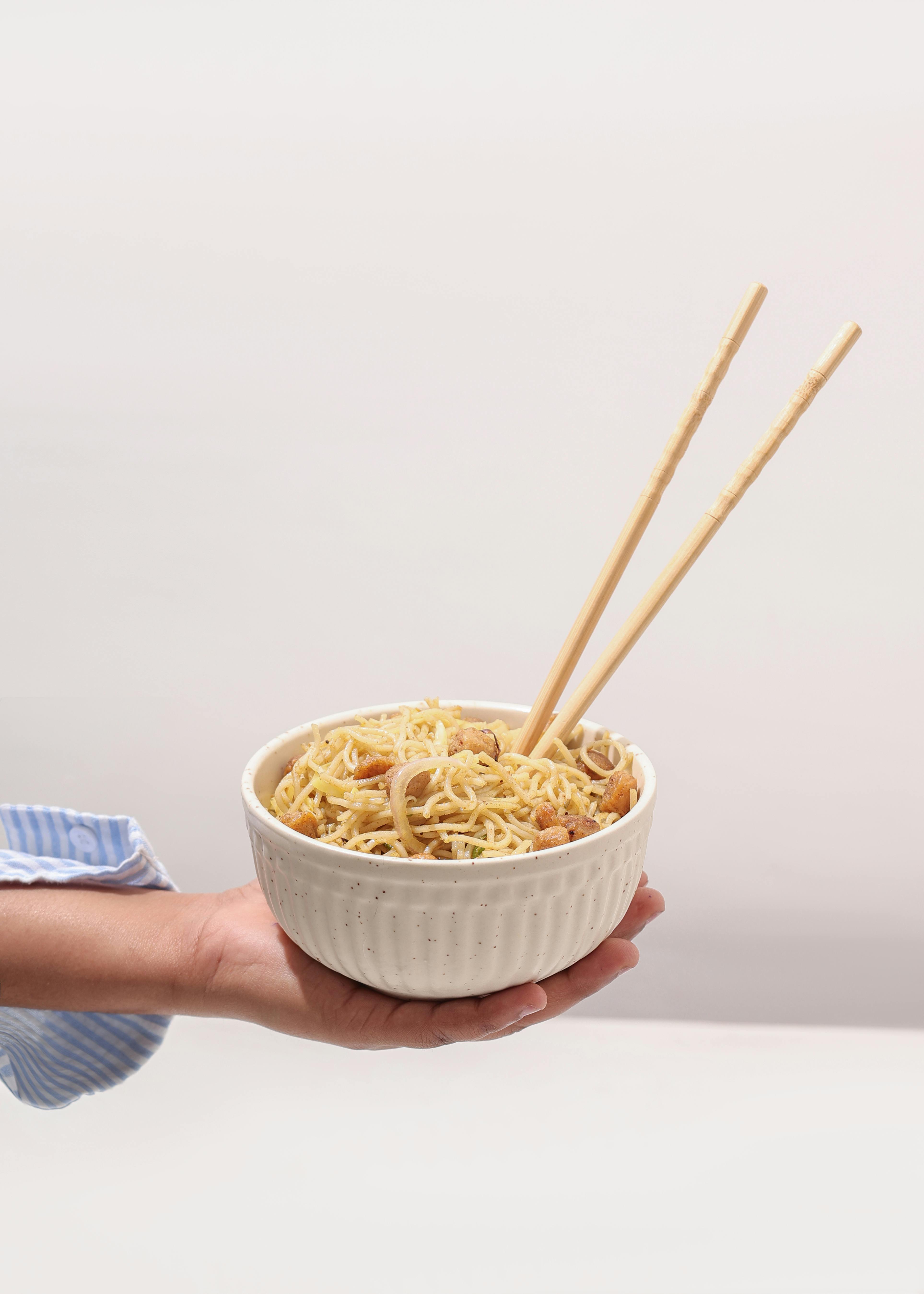 ฟรี ภาพระยะใกล้ของบะหมี่ที่เสิร์ฟในชามพร้อมตะเกียบ เหมาะสำหรับการจัดตกแต่งอาหาร คลังภาพถ่าย