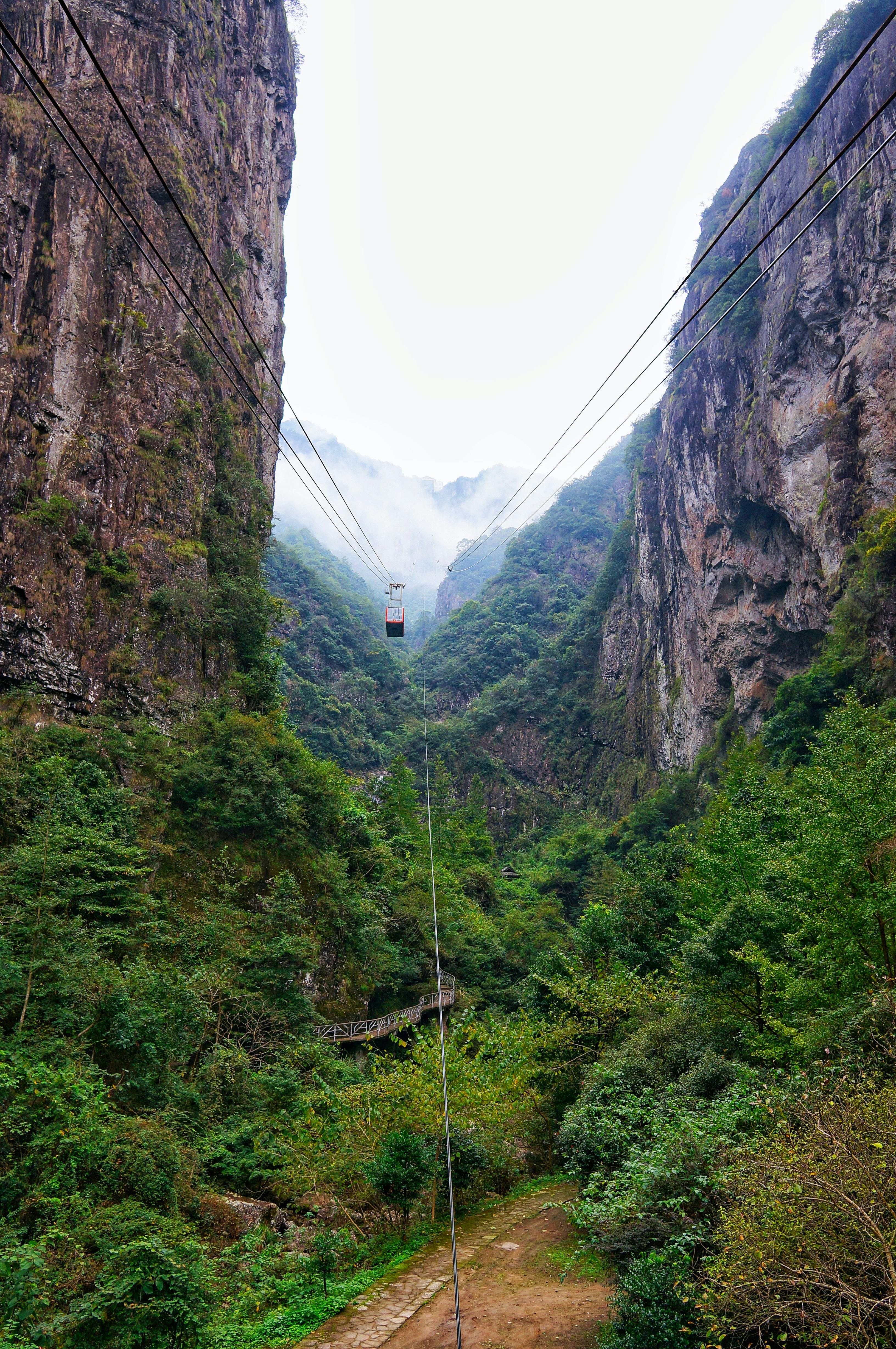 Zadarmo Preskúmajte úchvatný výhľad na kaňon lanovkou uprostred bujnej zelene a hmlistej oblohy. Fotka z fotobanky