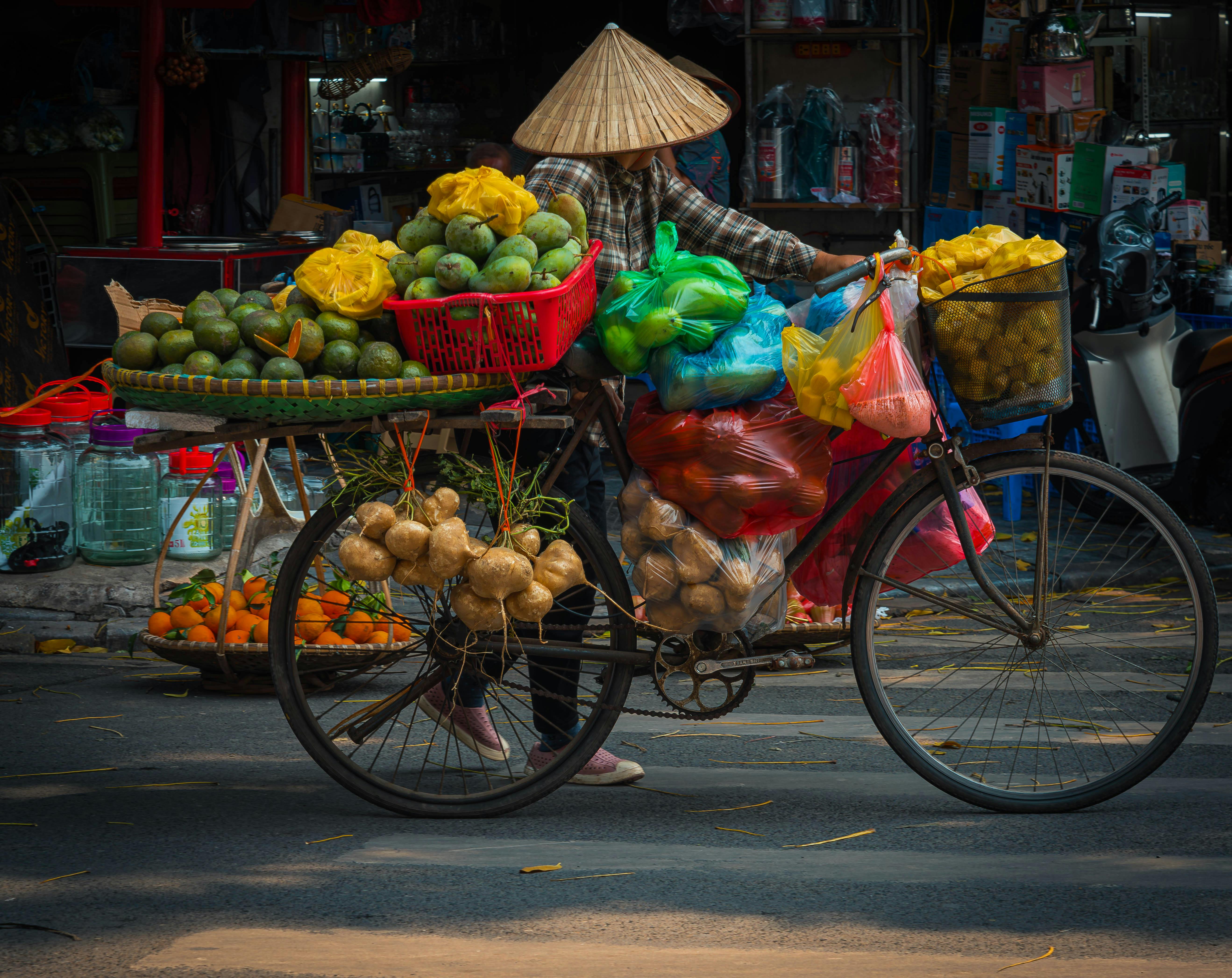 免费 在熙熙攘攘的市场里，一位街头小贩骑着自行车售卖新鲜农产品。 素材图片