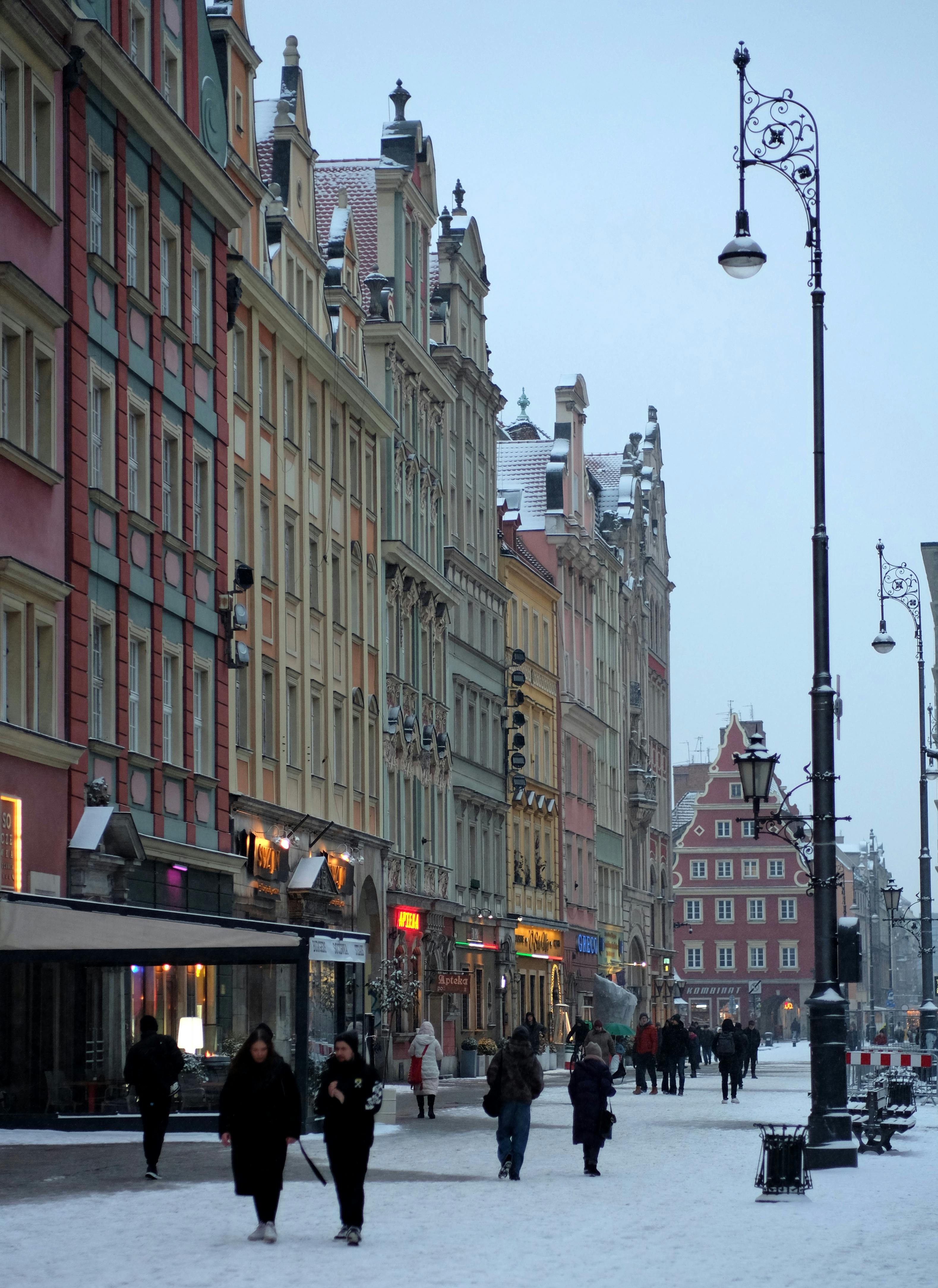 Zadarmo Zasnežená ulica v historickom európskom meste s farebnou architektúrou a chodcami počas dňa. Fotka z fotobanky