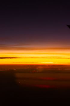 Experience a breathtaking aerial view during sunset with vivid colors merging above the clouds, perfect for travel and nature themes.