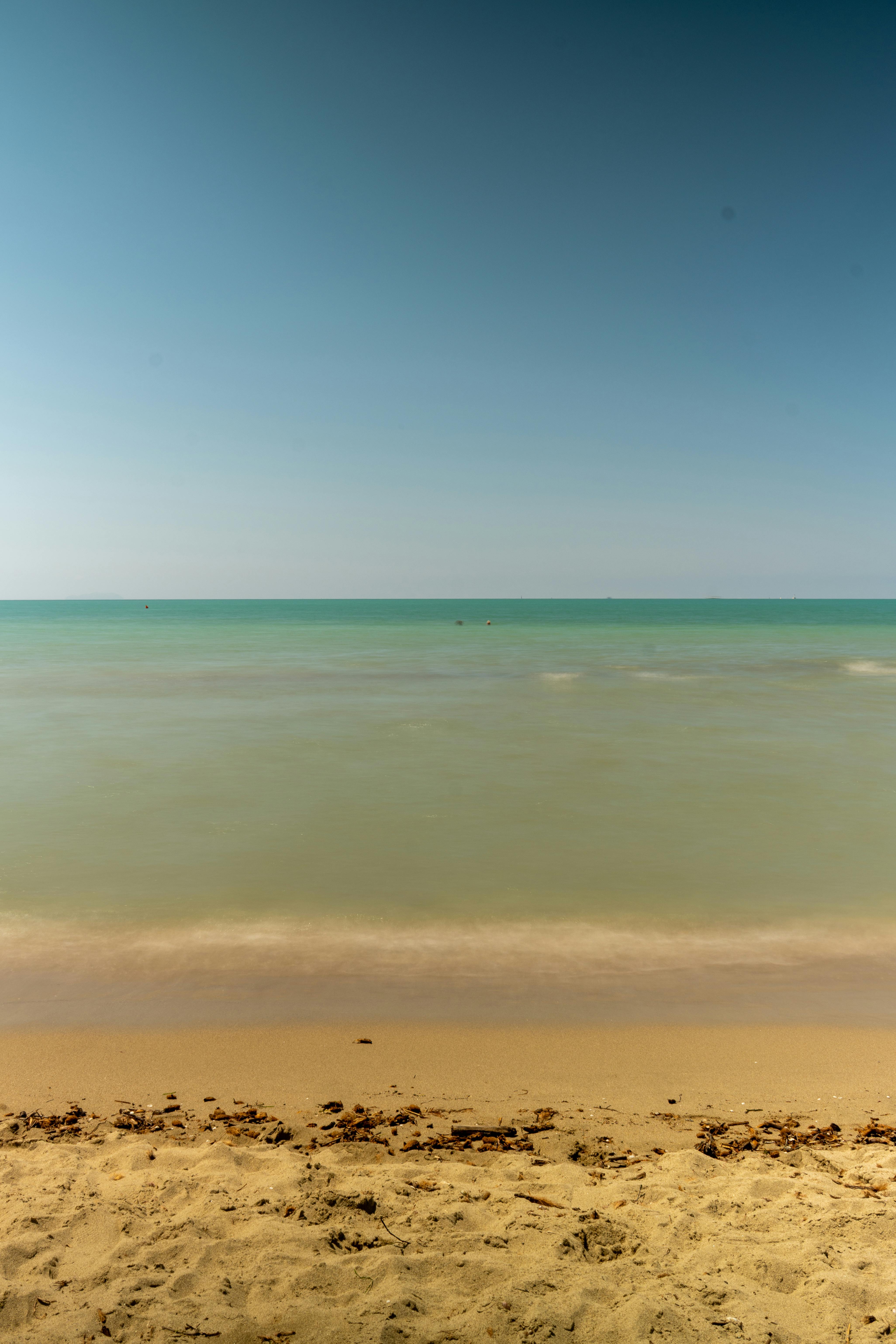 Zadarmo Pokojná plážová scenéria na talianskom pobreží zachytávajúca pokojné azúrové vody a piesočnaté pobrežie pod jasnou letnou oblohou. Fotka z fotobanky