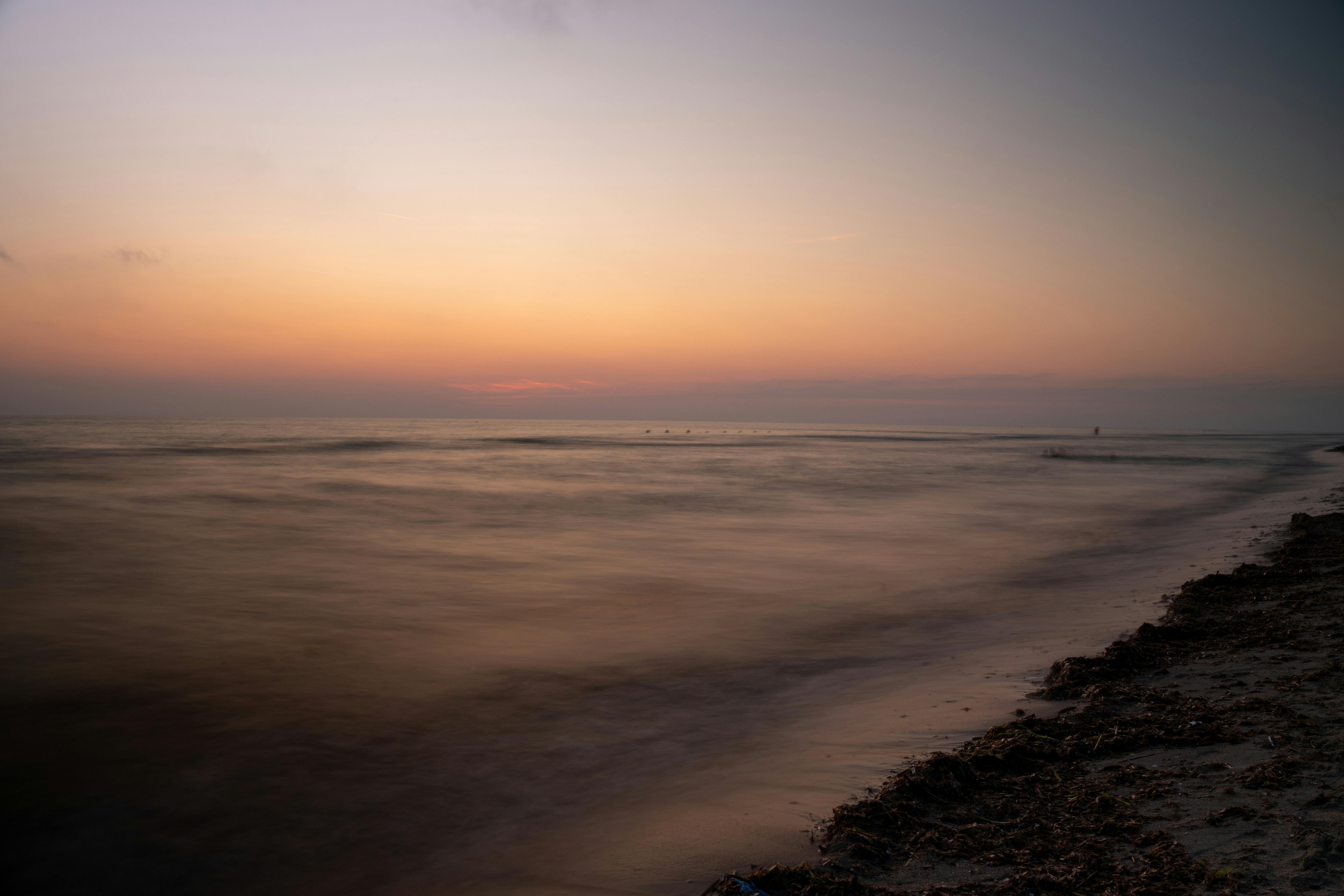 ฟรี ภาพถ่ายชายหาดอิตาลีอันเงียบสงบยามพระอาทิตย์ตกดิน น้ำทะเลสงบนิ่ง และเส้นขอบฟ้าดูงดงาม คลังภาพถ่าย