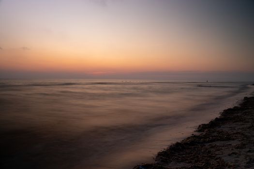 Capture of a serene Italian beach at sunset, with calm waters and a peaceful horizon.