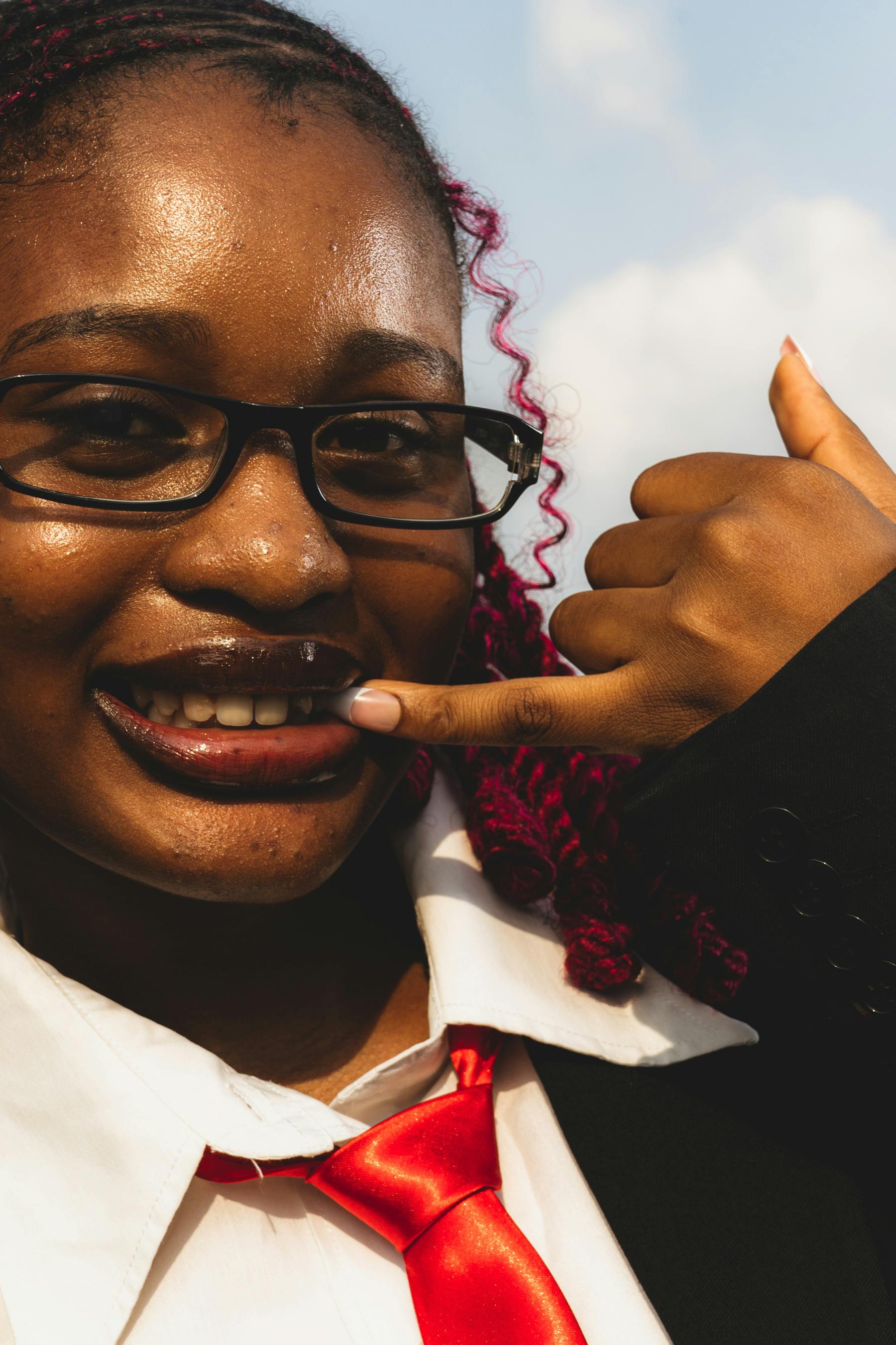 免費 特寫鏡頭：一位身著職業裝的微笑女士在藍天下用手比劃著打電話的手勢。 圖庫相片