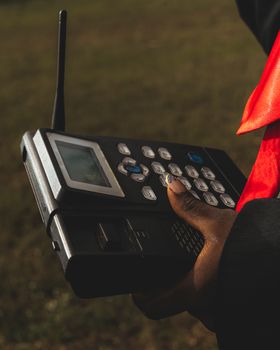 Close-up of a person operating a vintage two-way radio device outdoors on a sunny day.