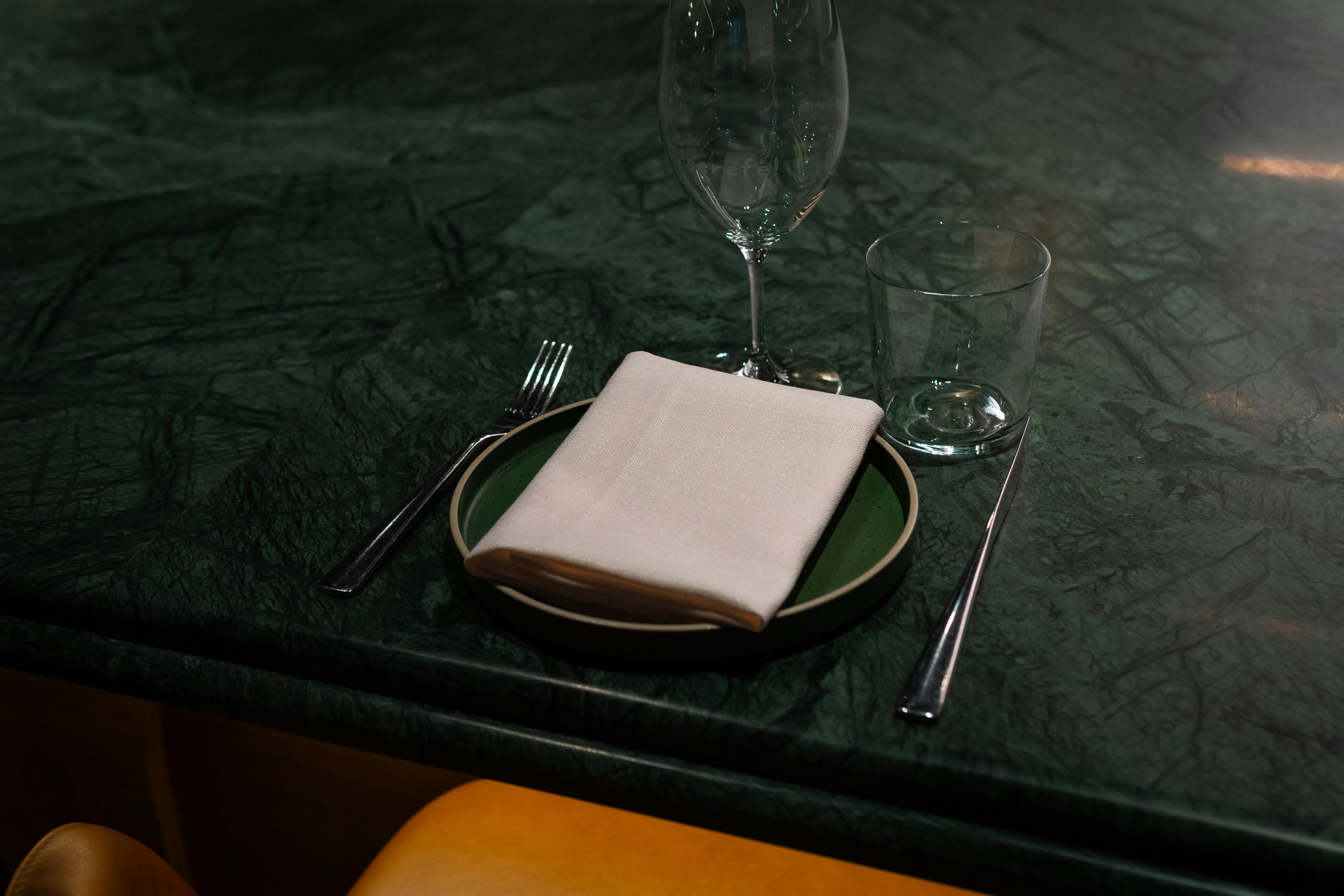 ingyenes Stílusos asztalterv szalvétával, villával és poharakkal egy zöld márványpulton. Stockfotó