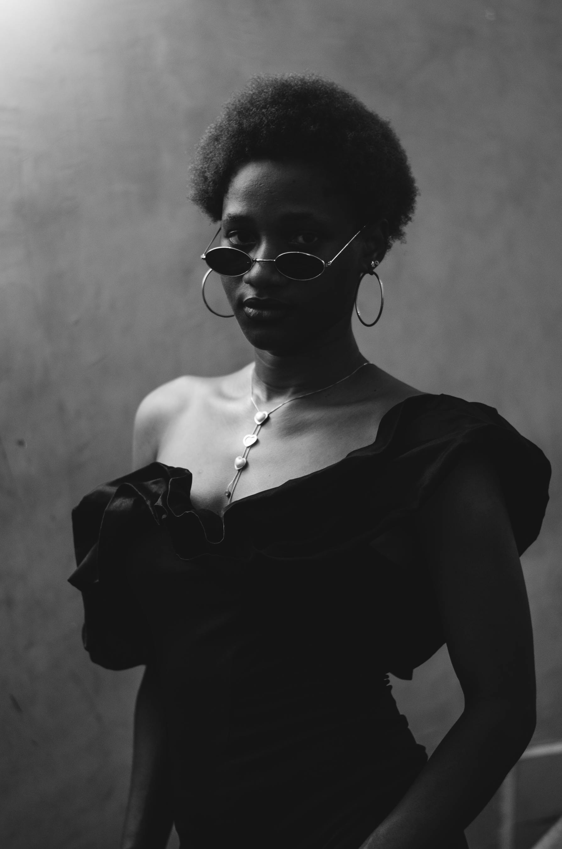 免費 一張極具戲劇性的黑白肖像照，照片中的時尚女性戴著太陽眼鏡，穿著優雅的服裝。 圖庫相片