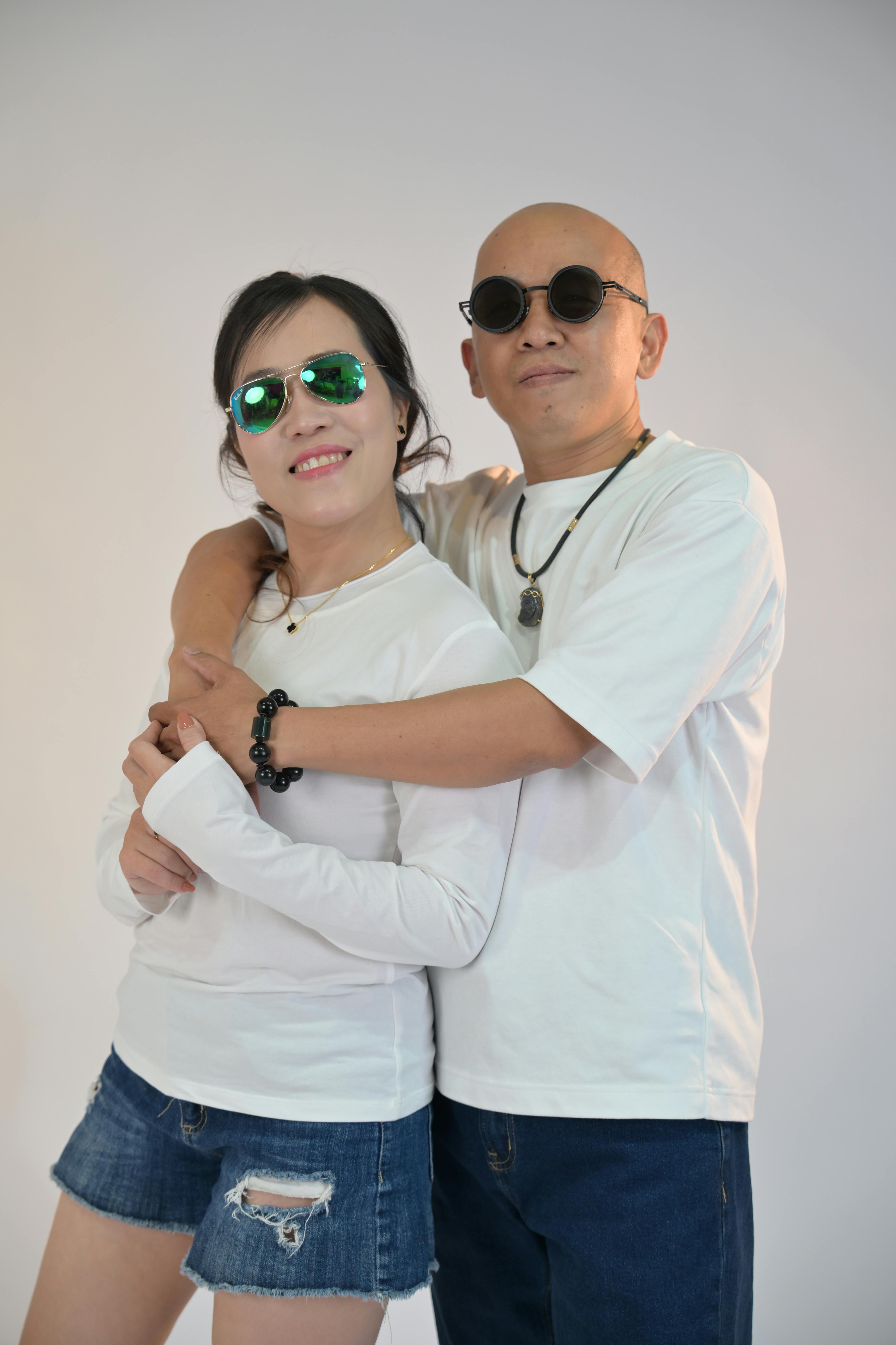 bezplatná Veselý pár v ležérních oblecích a slunečních brýlích pózuje na prostém pozadí. Základová fotografie