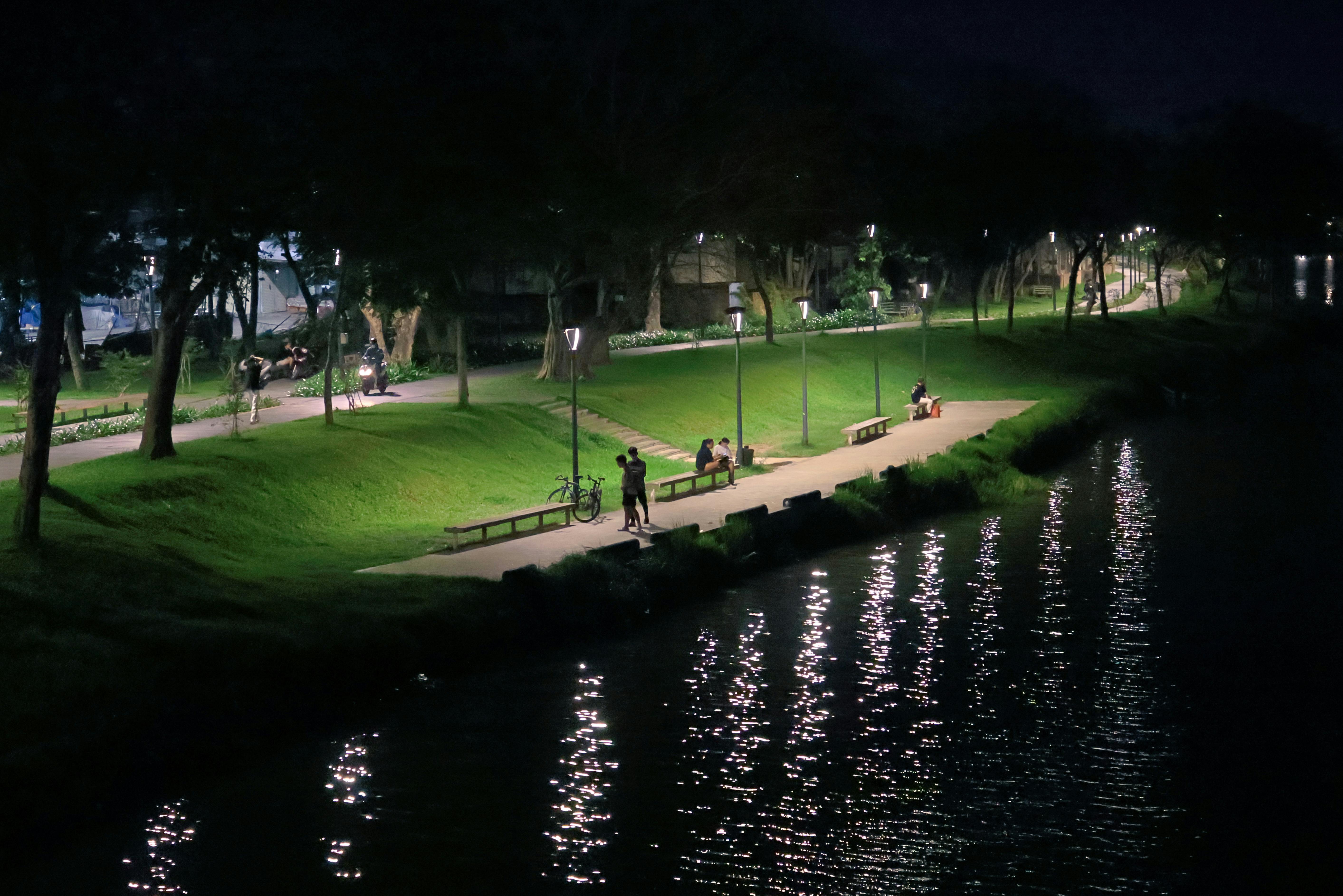 Kostenlos Friedliche Abendszene am Fluss in Hue mit beleuchteten Wegen und Spiegelungen auf dem Wasser. Stock-Foto