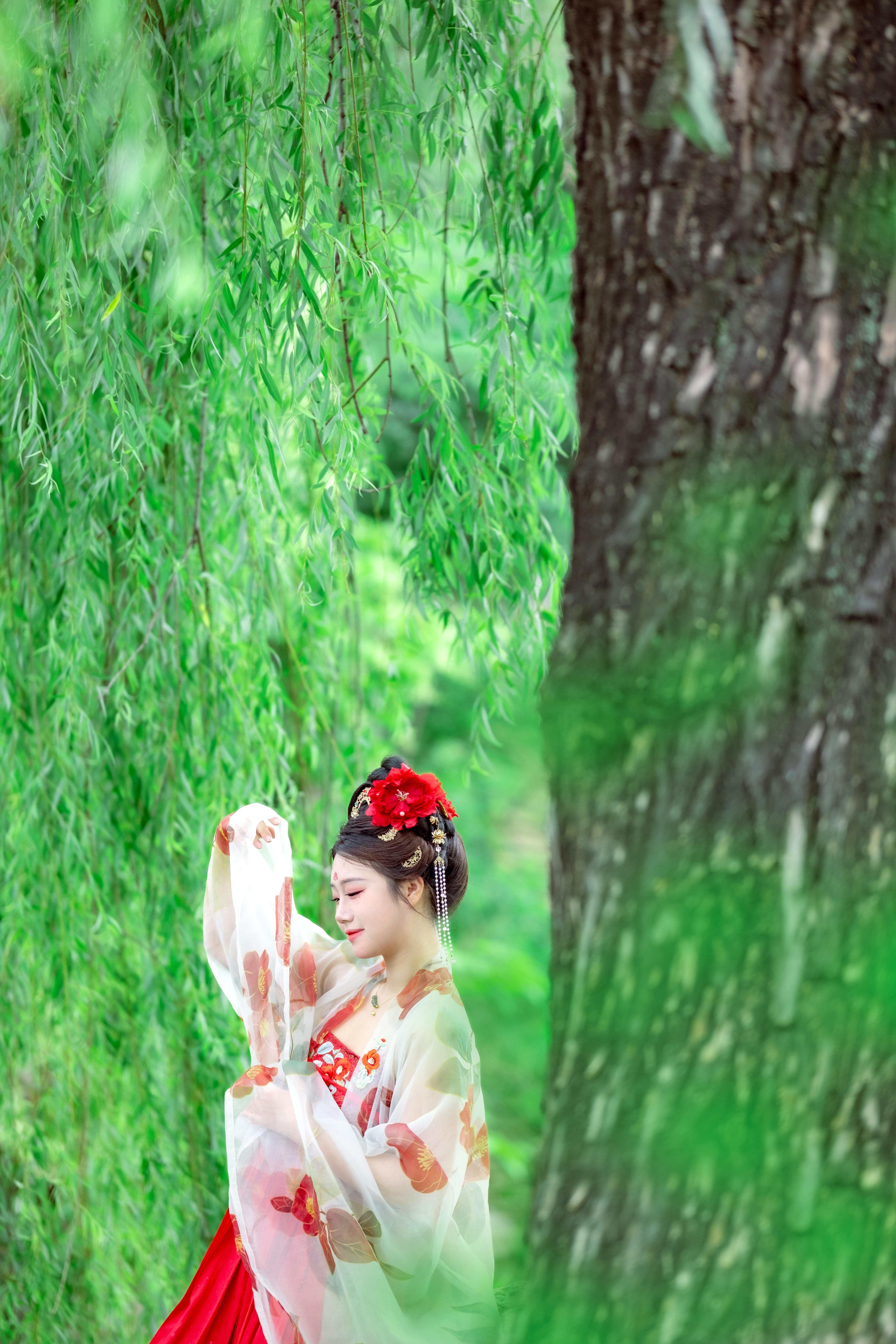 ingyenes Elegáns nő hagyományos öltözékben, buja zöld lombozat alatt, kulturális kecsességet idézve. Stockfotó