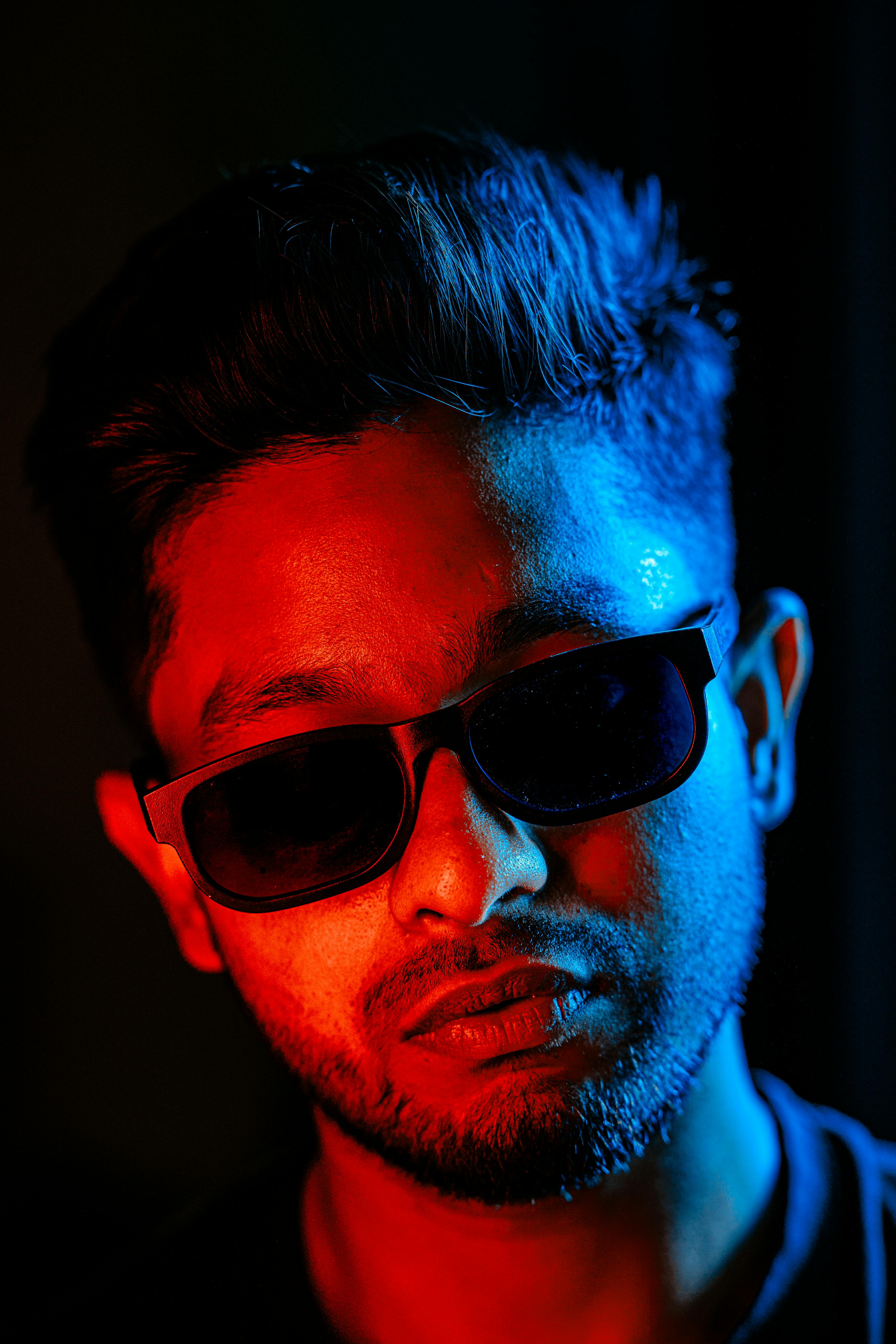 Zadarmo Živý portrét muža v slnečných okuliaroch s modrým a červeným osvetlením. Fotka z fotobanky