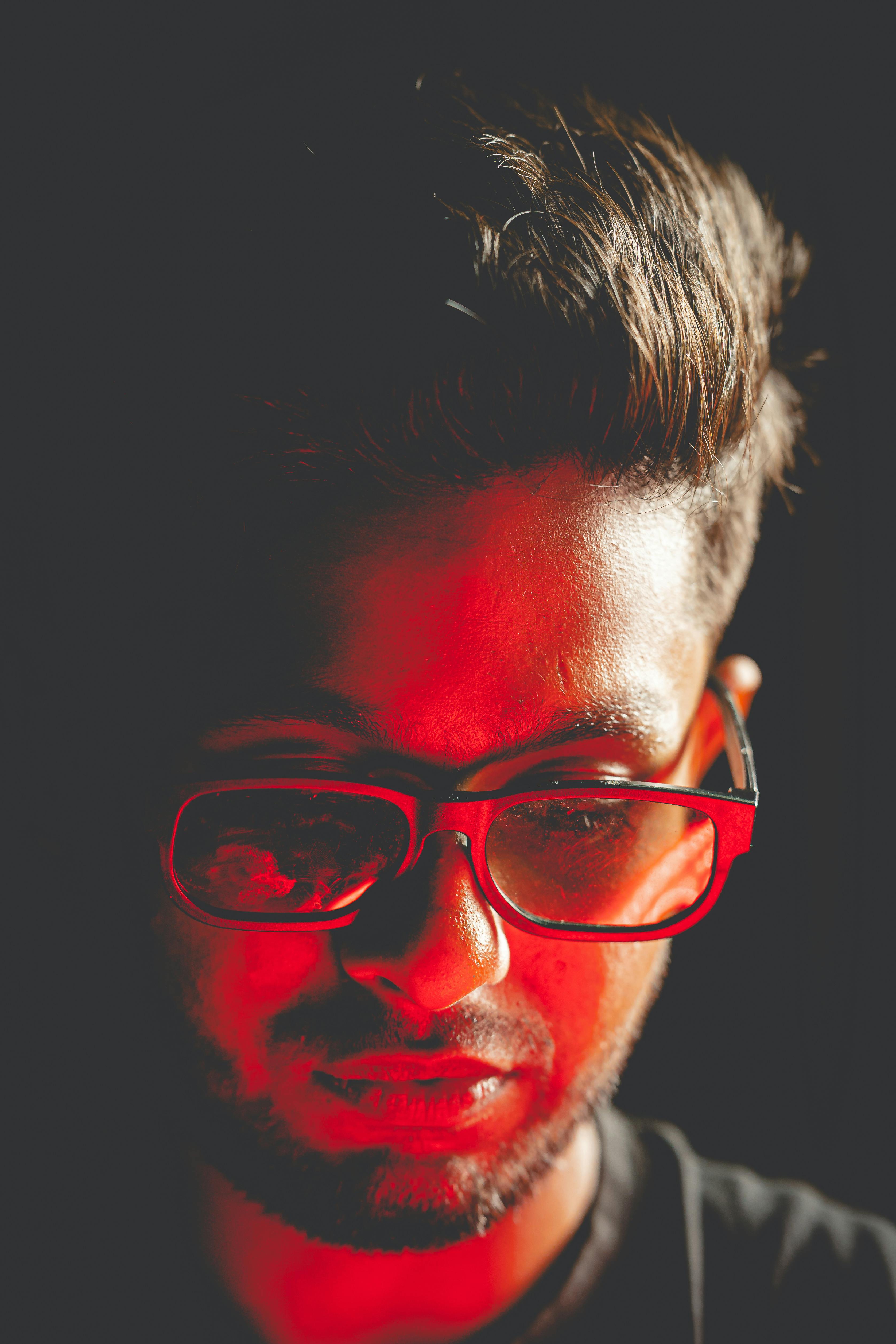 Безкоштовне Драматичний крупний план чоловіка в червоному освітленні, що створює похмурий та художній ефект. стокове фото