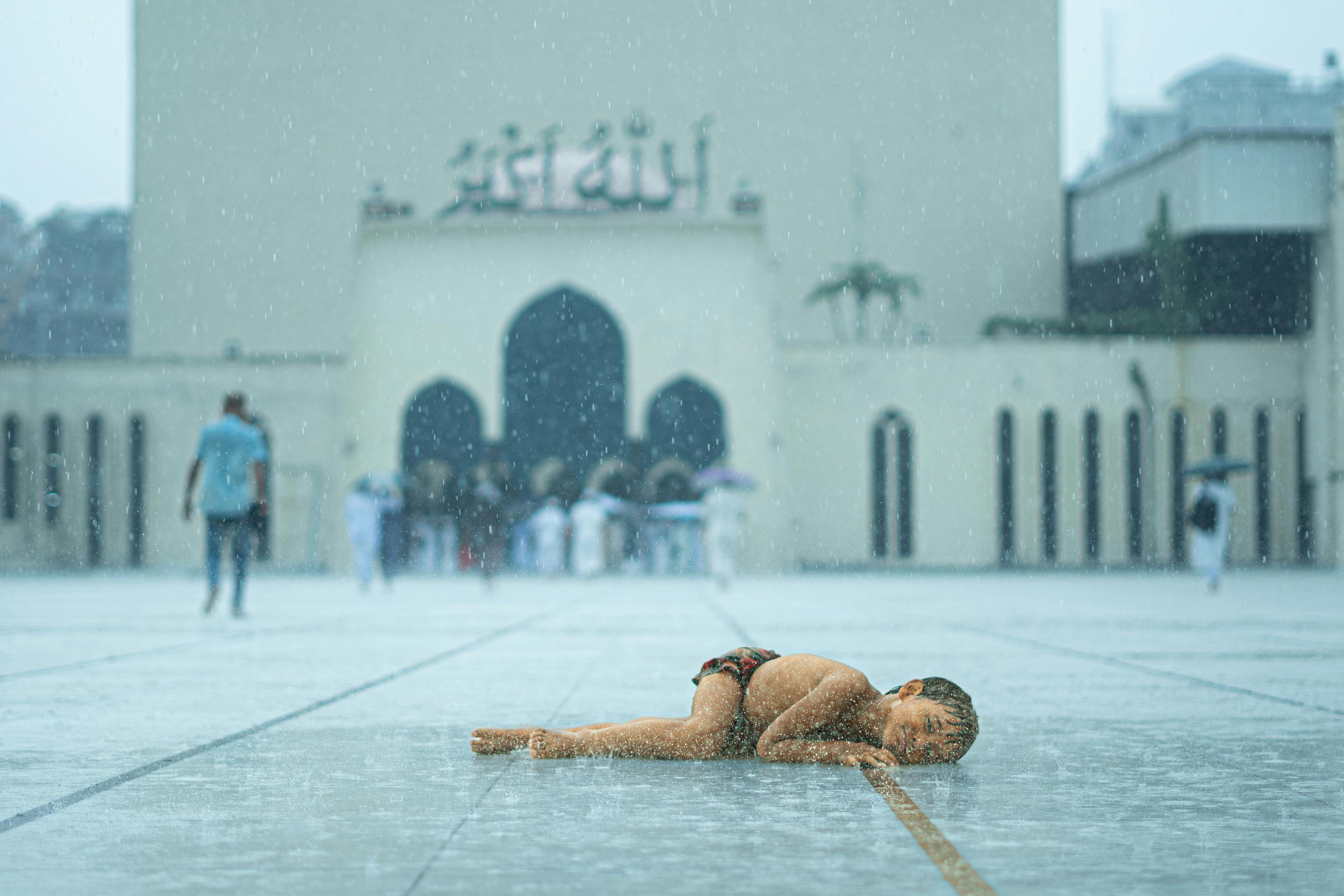 免费 雨中，一名儿童睡在孟加拉国达卡一座清真寺外。 素材图片