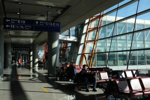 Free Bright modern airport terminal with seated passengers and directional signs. Stock Photo