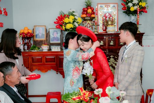 A heartwarming hug during a traditional Vietnamese wedding celebration indoors.