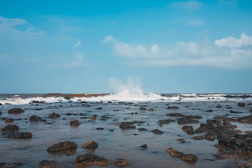Free Captivating view of waves crashing on a rocky shore under clear blue skies. Stock Photo