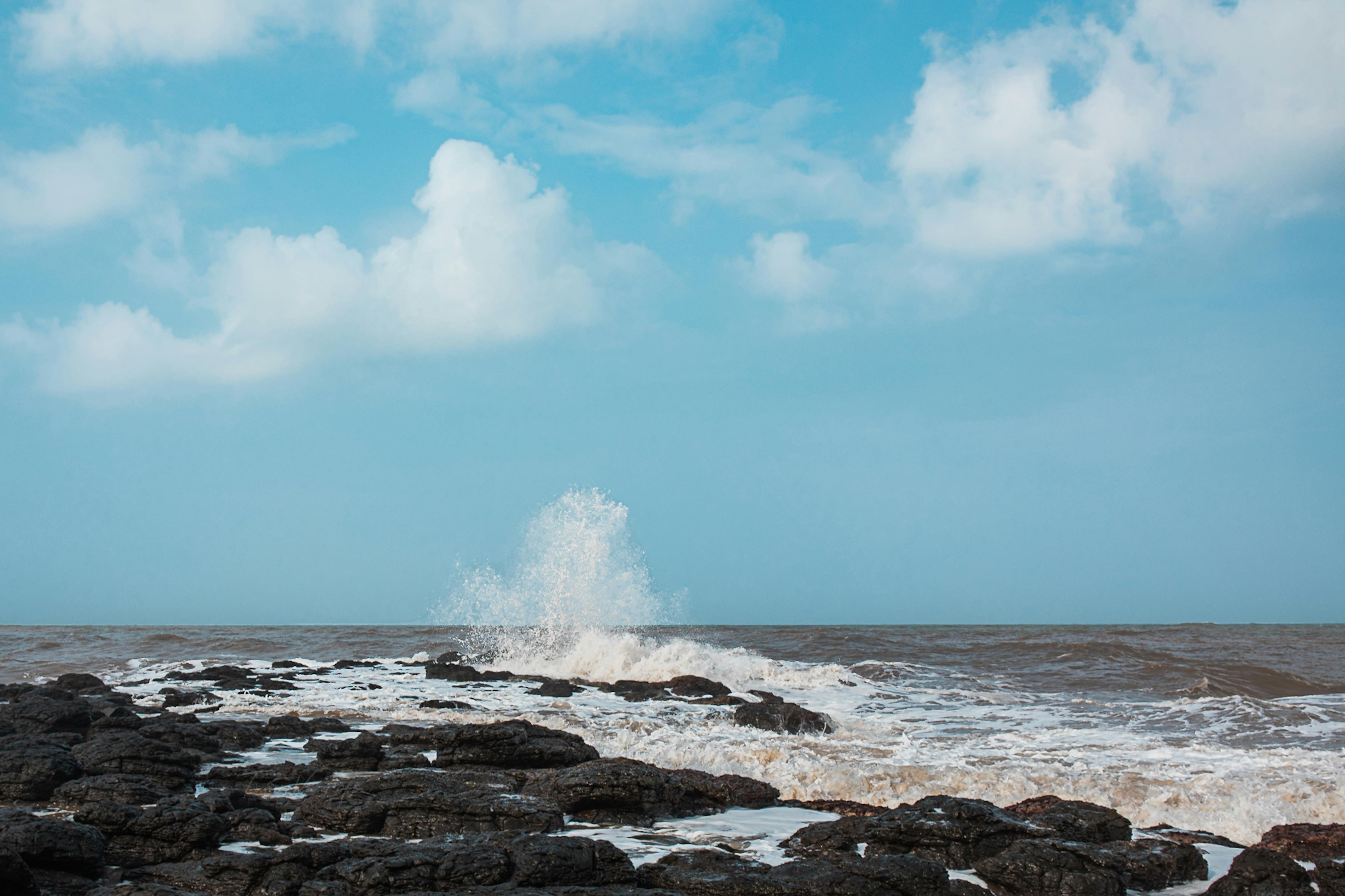 免费 海浪拍打着岩石海岸，蓝天白云，构成一幅动感十足的画面。 素材图片