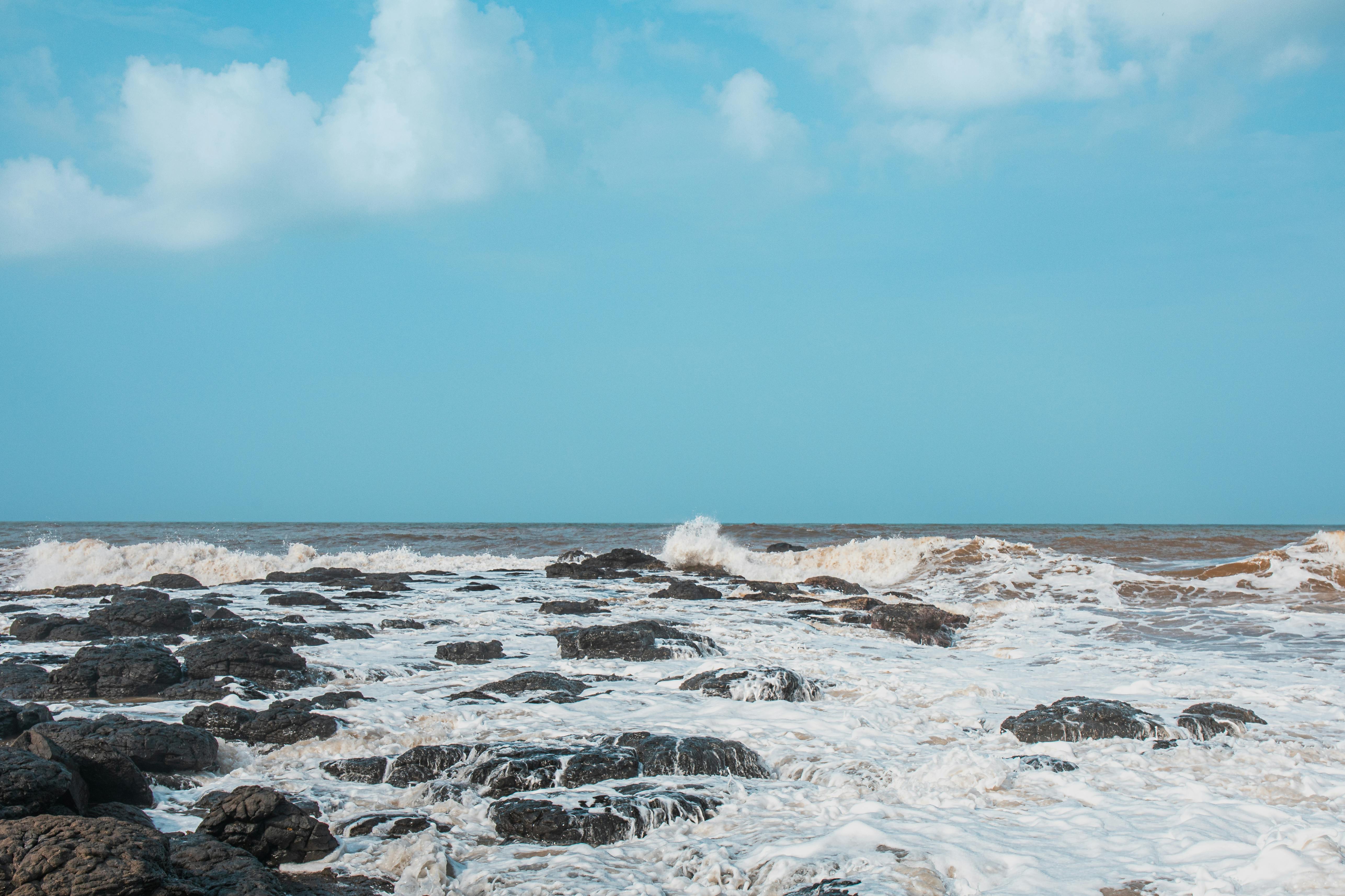 免費 在湛藍的天空下，洶湧的波濤拍打著岩石海岸，展現了大自然的磅礴力量。 圖庫相片