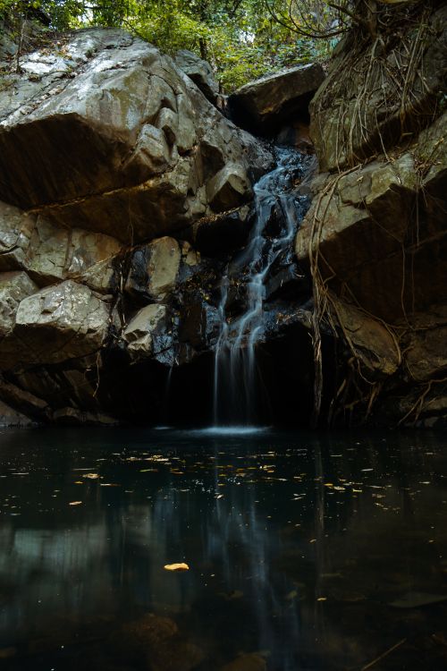 Free A tranquil waterfall flows in the forested rocks of Ghatshila, India, offering a serene natural retreat. Stock Photo