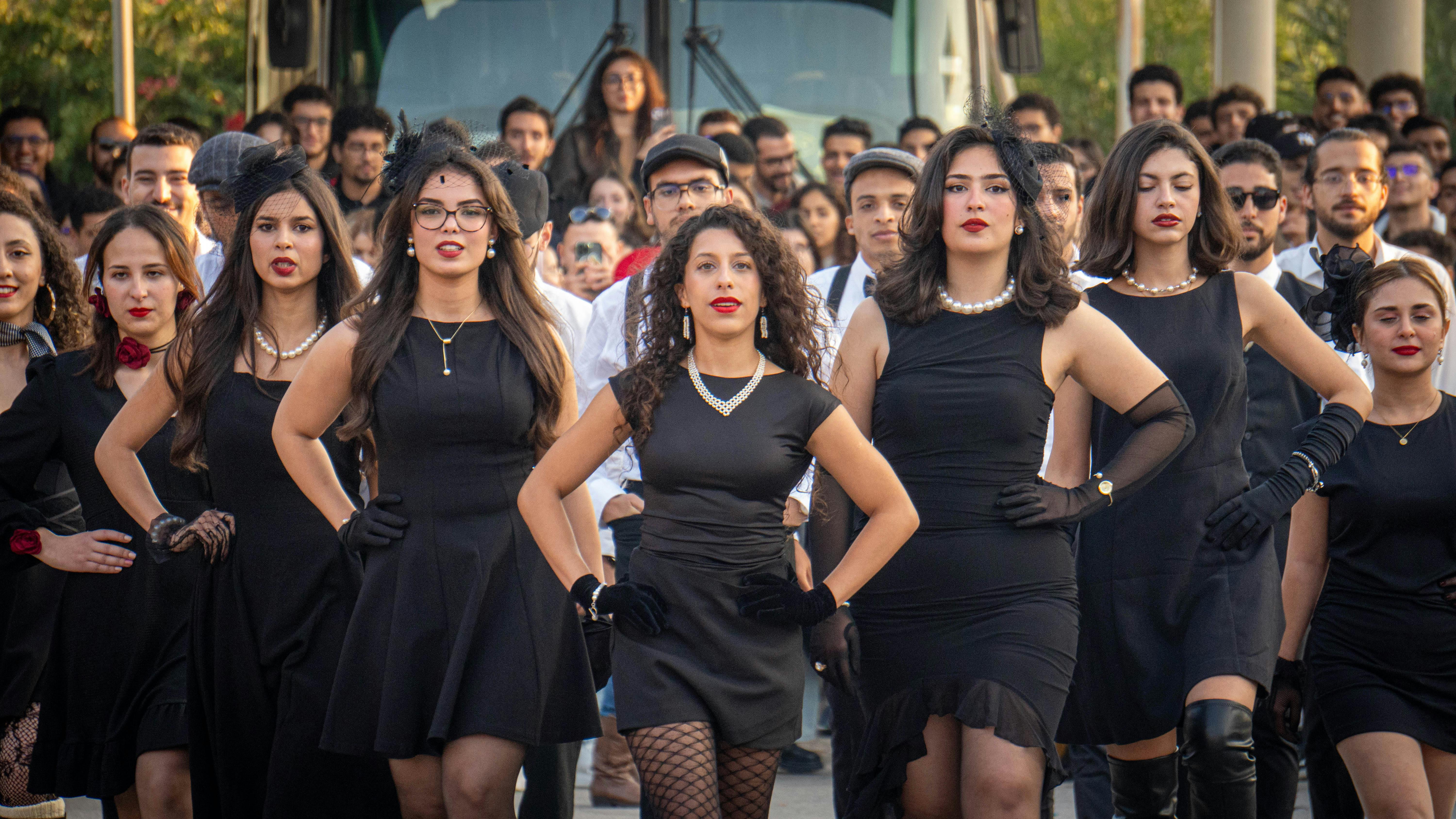 Zadarmo Skupina dospelých v elegantnom čiernom oblečení a retro móde sebavedomo kráčajú v sprievode. Fotka z fotobanky