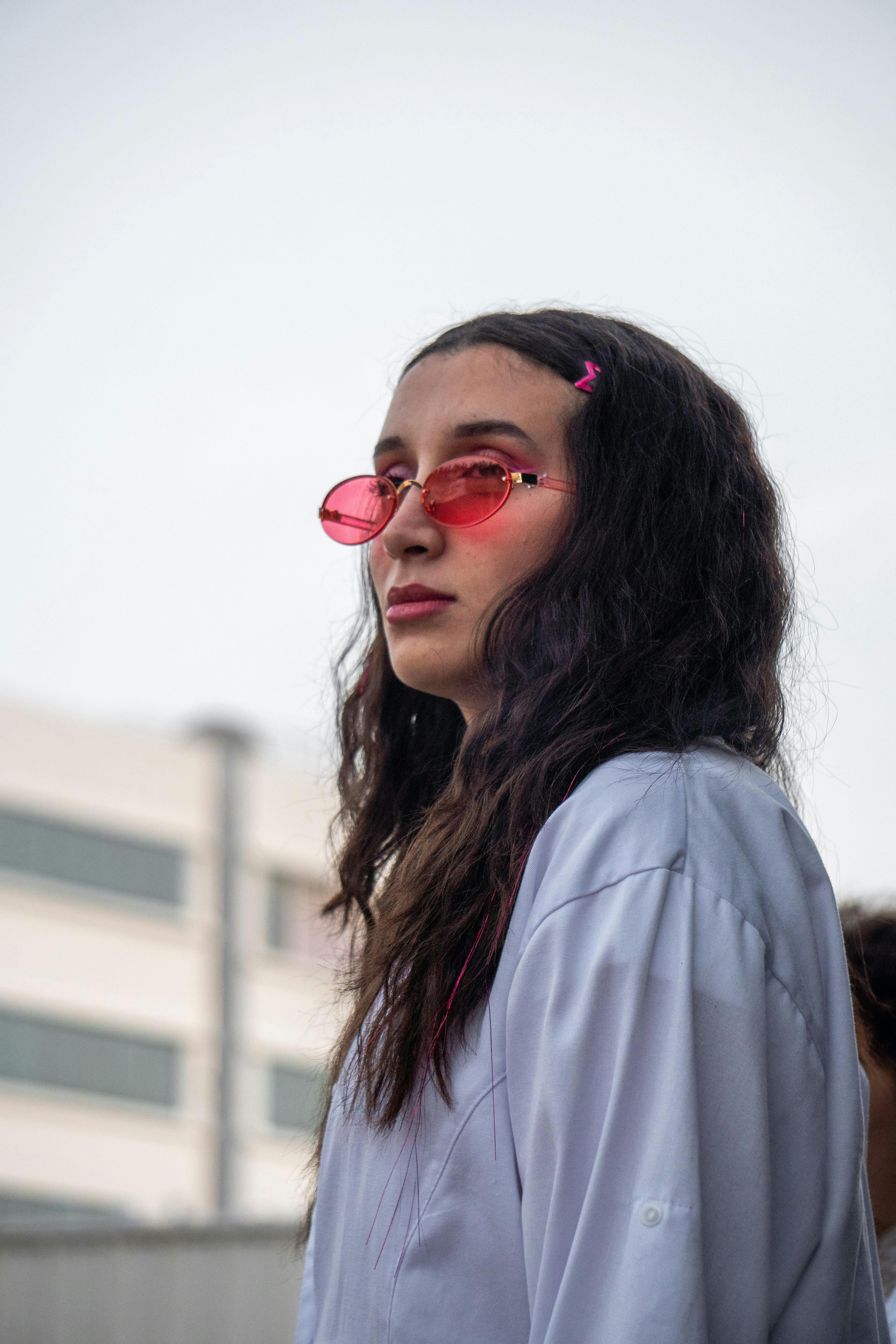 免費 一位戴著紅色太陽眼鏡、穿著休閒裝的時尚女士在戶外，展現了都市時尚風采。 圖庫相片