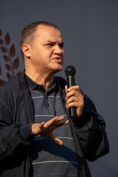 A charismatic speaker captivates the audience with a microphone during an outdoor event.
