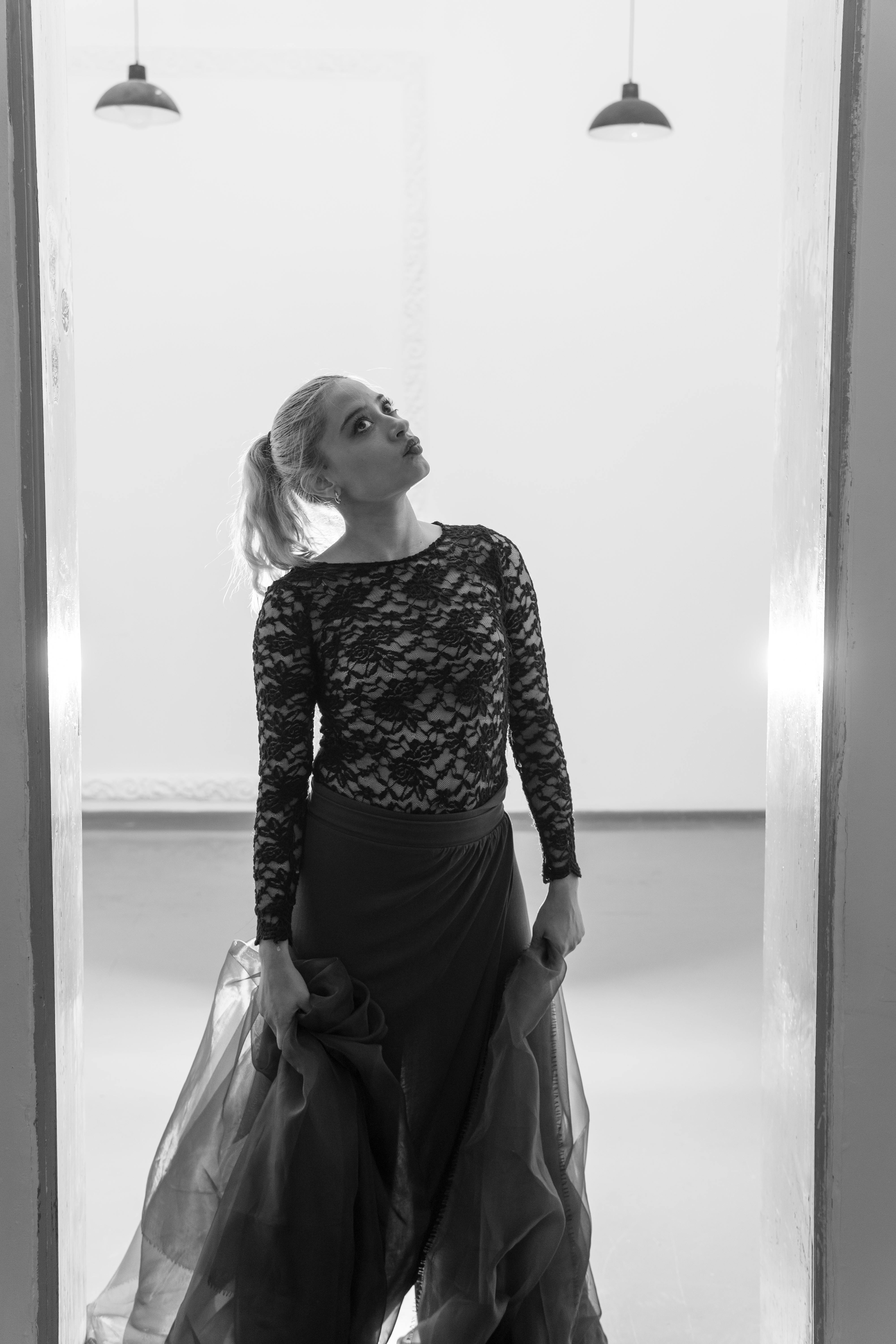 ingyenes Kecses pózban, csipkeruhában táncoló női táncos, kifinomult fekete-fehér környezetben. Stockfotó