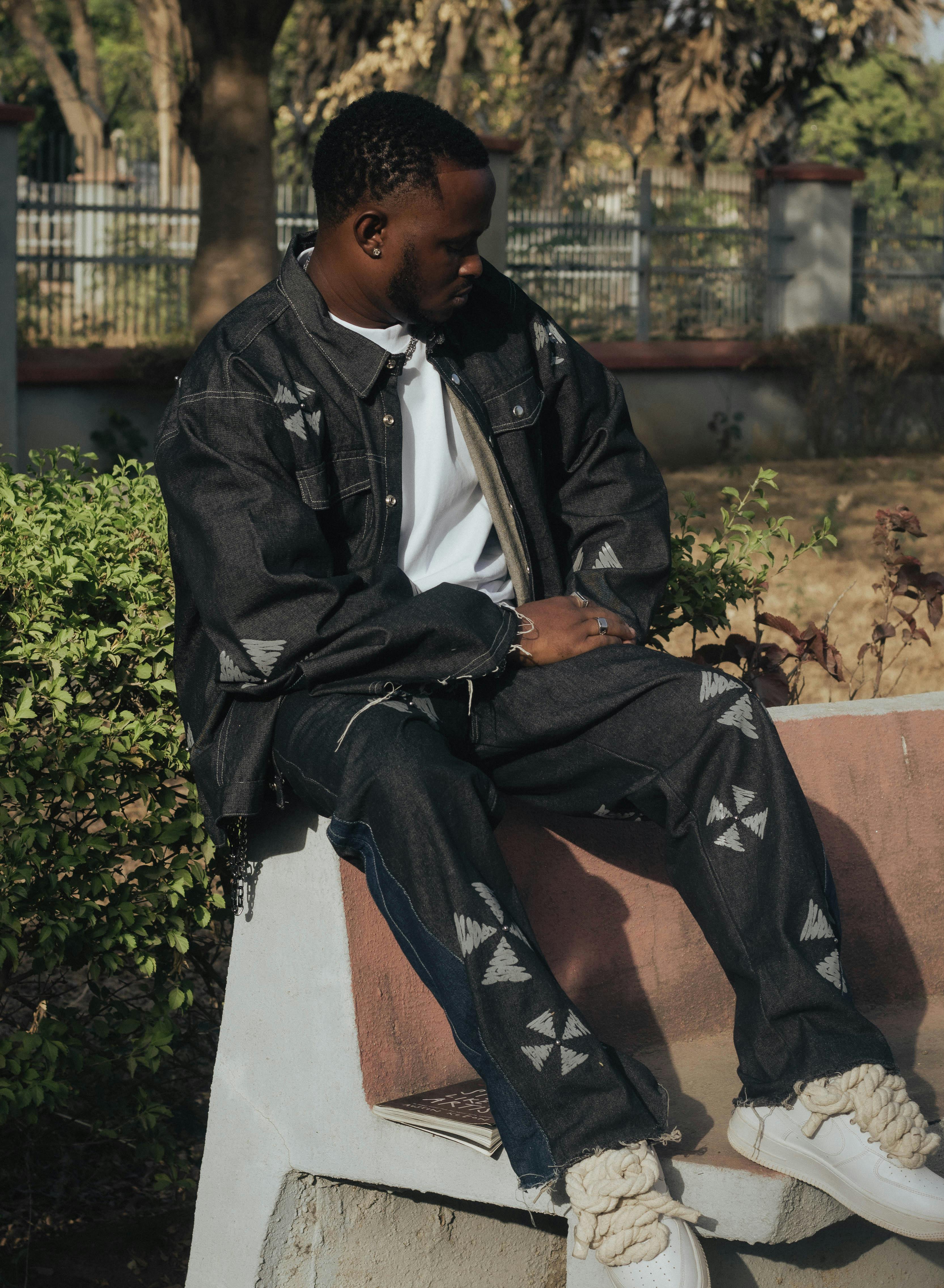 Zadarmo Muž v džínsovom oblečení sedí vonku a ukazuje štýlovú ležérnu módu. Fotka z fotobanky