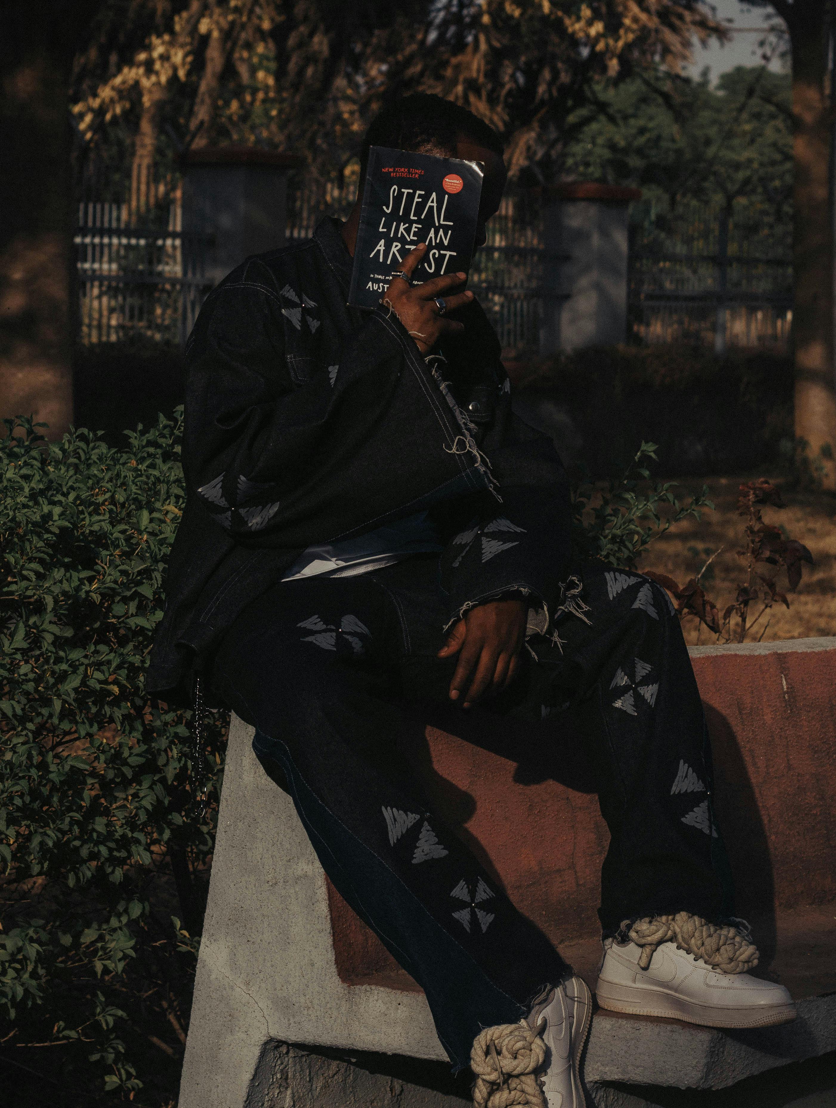 Zadarmo Módna osoba v vonkajšom prostredí číta knihu „Kradni ako umelec“ od Austina Kleona. Fotka z fotobanky