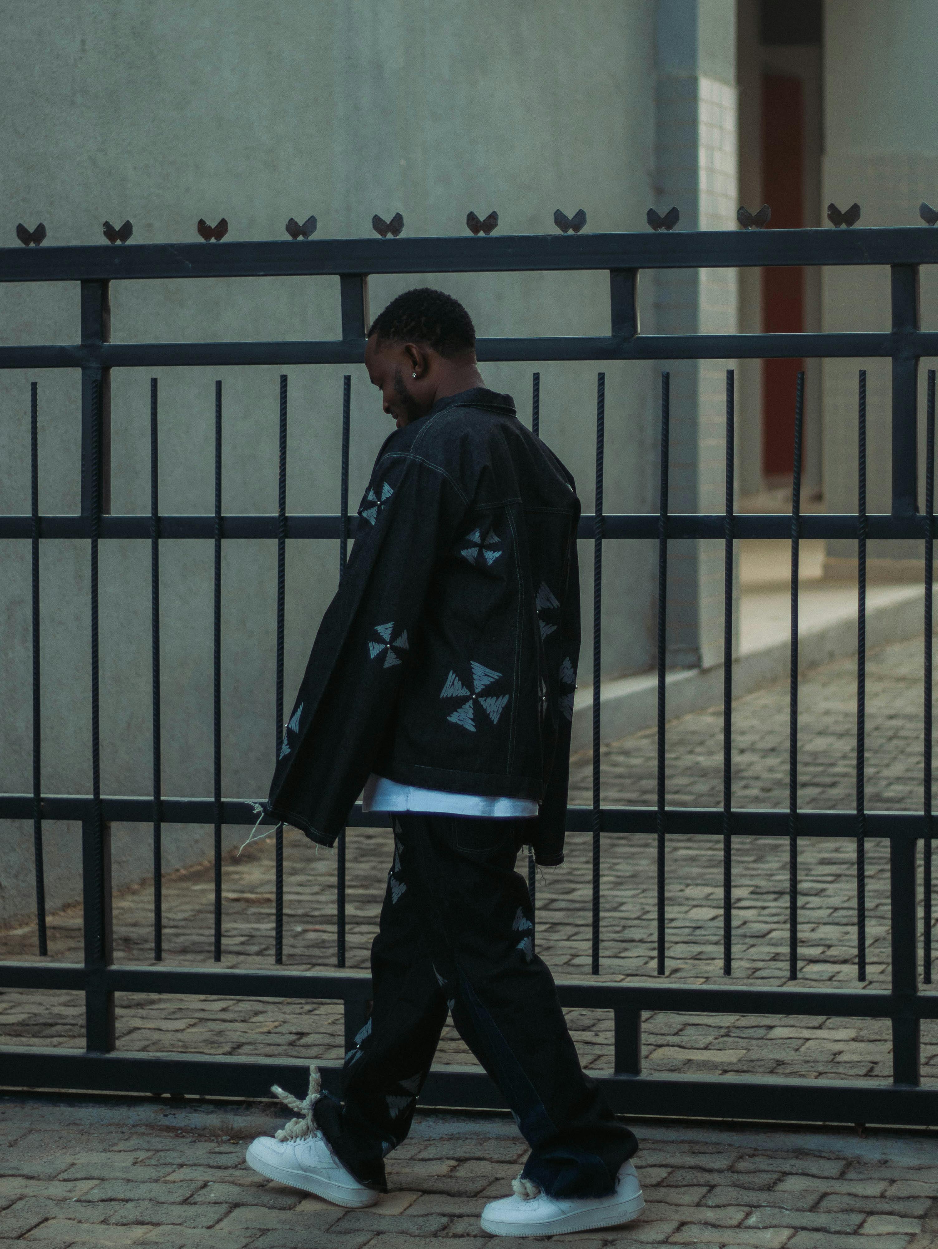 Zadarmo Muž v štýlovom mestskom oblečení kráčajúci pozdĺž moderného plota budovy Fotka z fotobanky