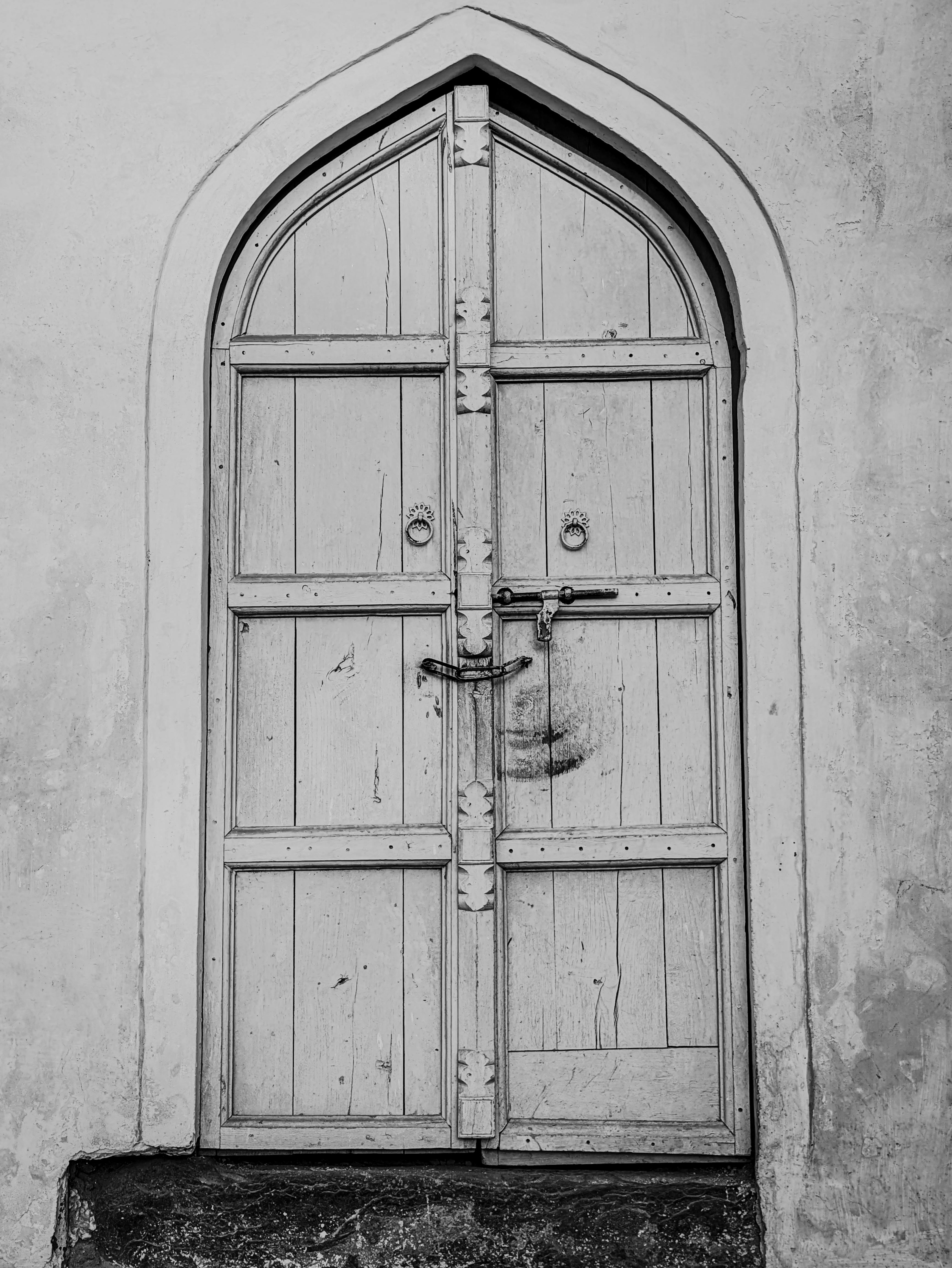 Безкоштовне Чорно-біле фото арочних дерев'яних дверей з вінтажними деталями, що створює класичну та художню атмосферу. стокове фото