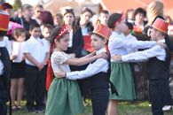 Children in costumes performing a traditional dance at an outdoor event, lively atmosphere.