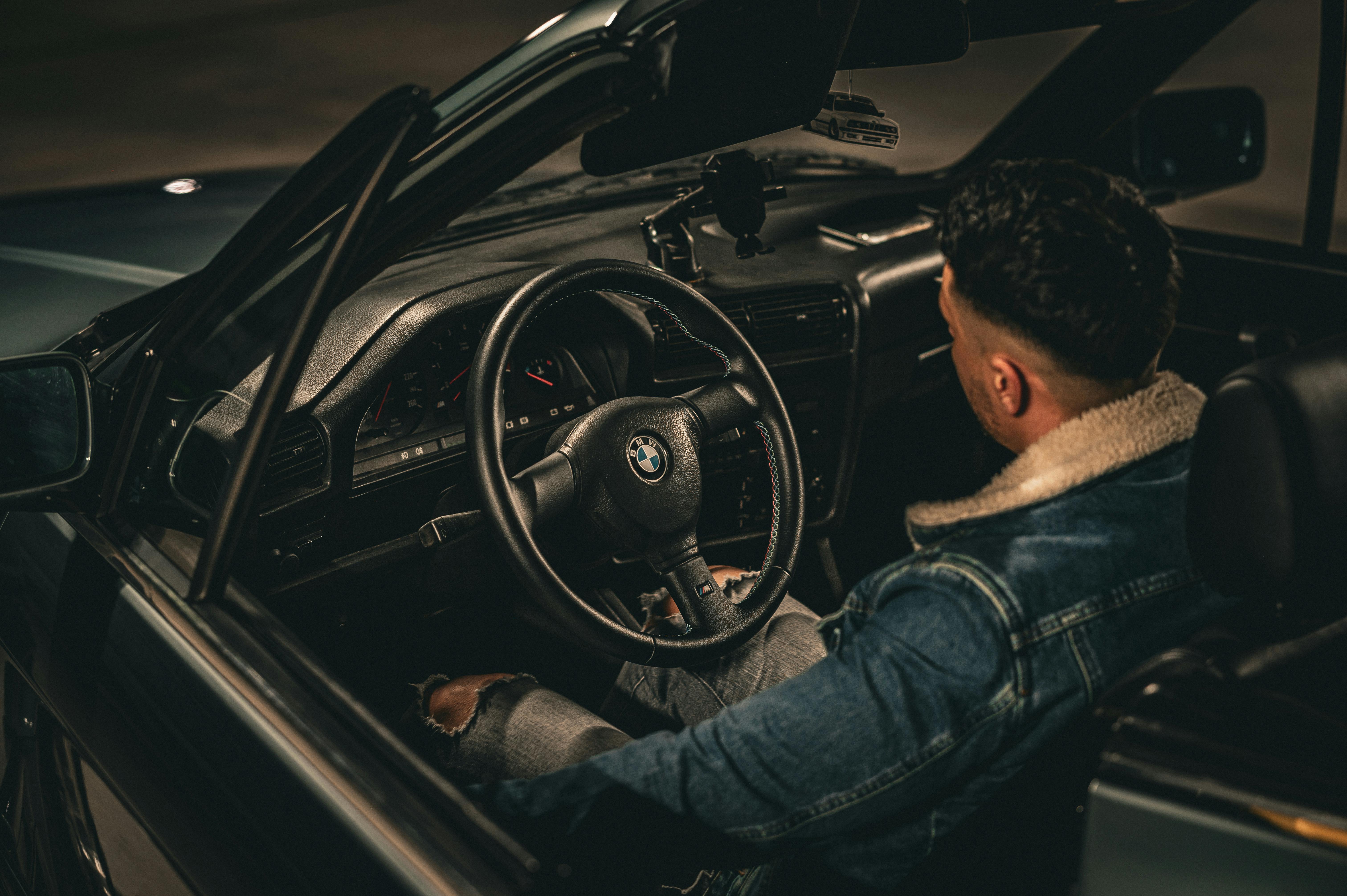 免费 一位身穿牛仔夹克的男子夜间驾驶着敞篷车。昏暗的灯光营造出温馨的氛围。 素材图片