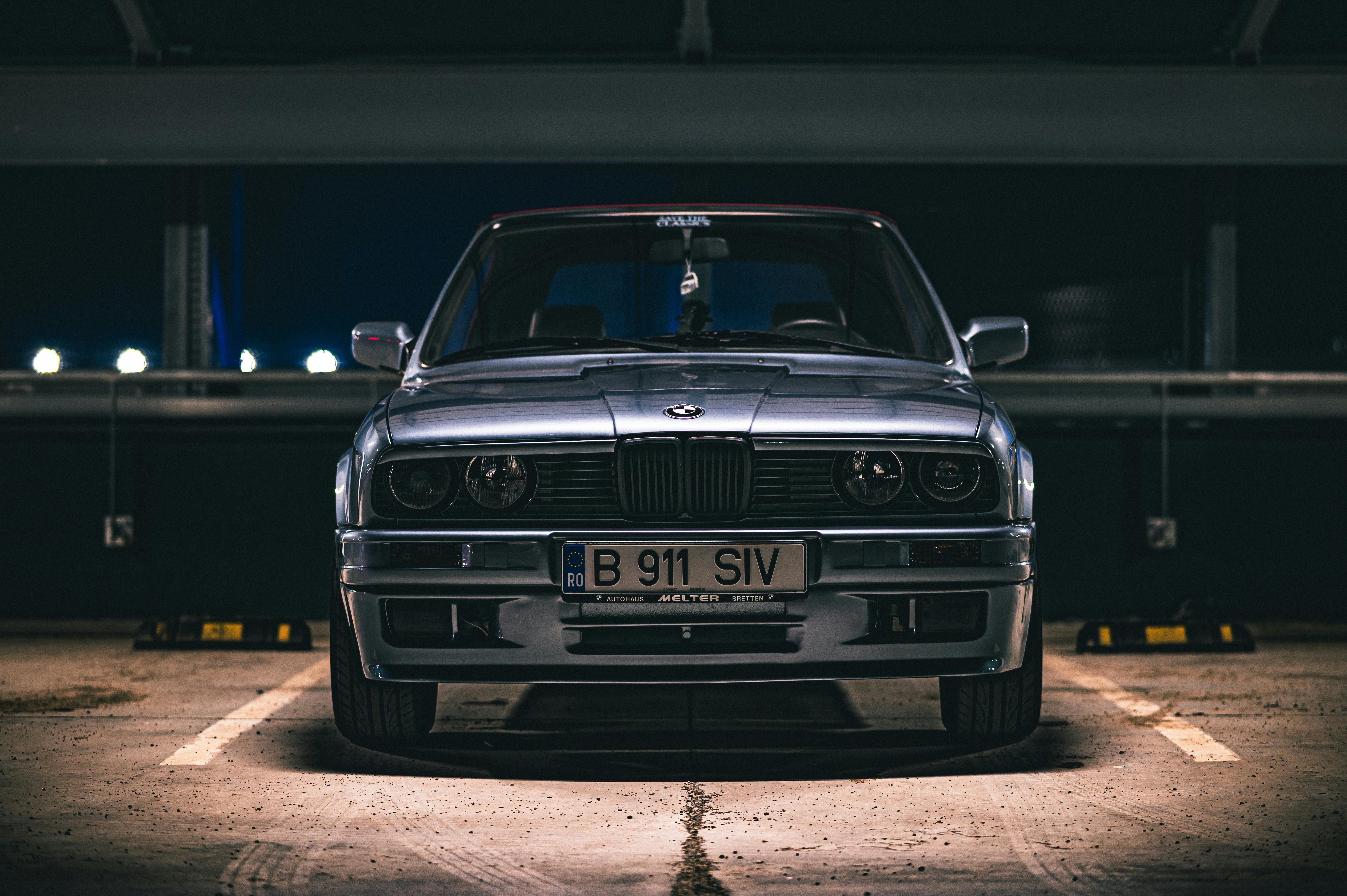 Front view of a vintage BMW parked in an urban garage with moody lighting.