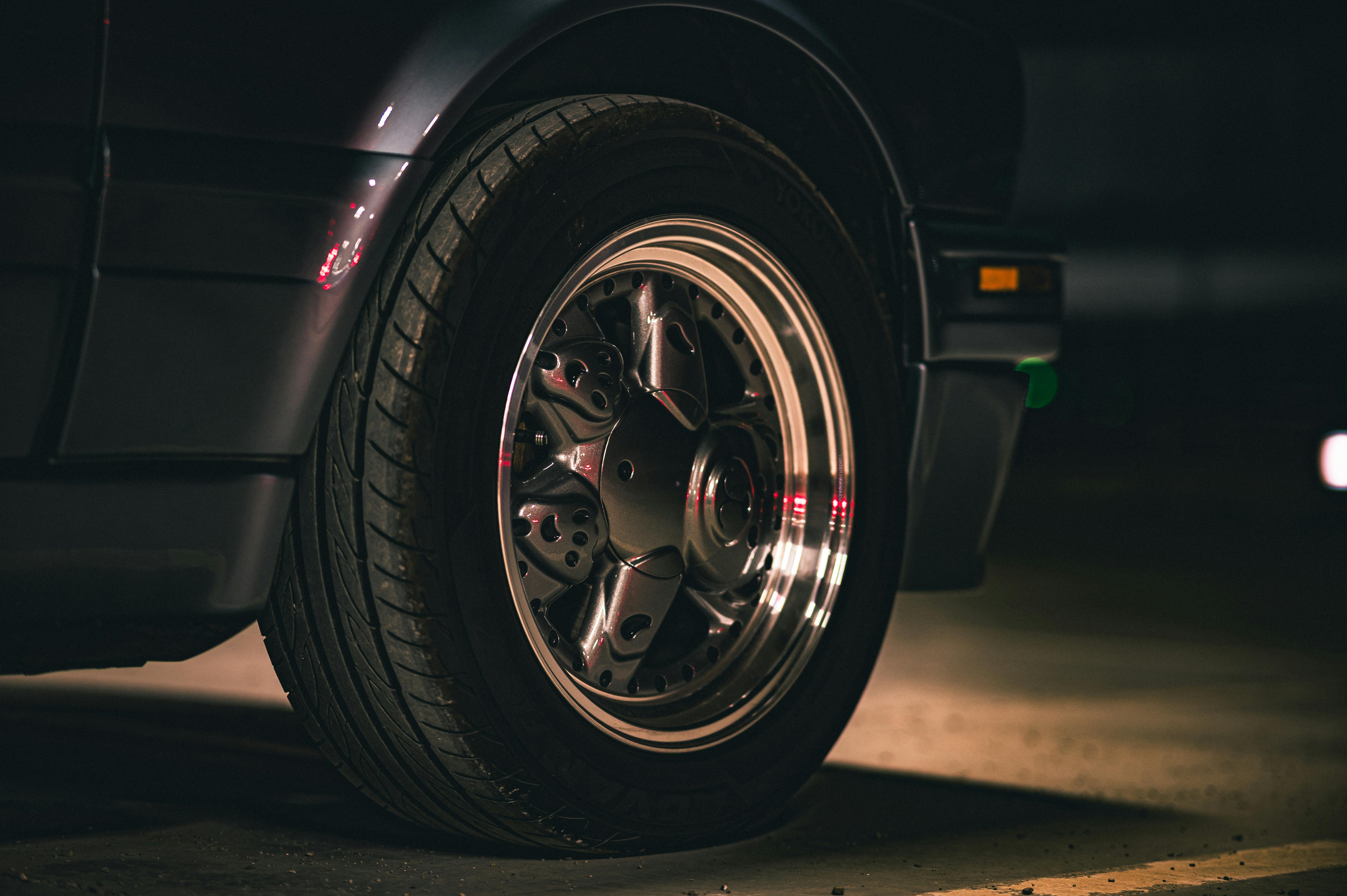 Zadarmo Detailný záber kolesa klasického auta v tlmenom osvetlení, s dôrazom na elegantný dizajn a kovovú povrchovú úpravu. Fotka z fotobanky