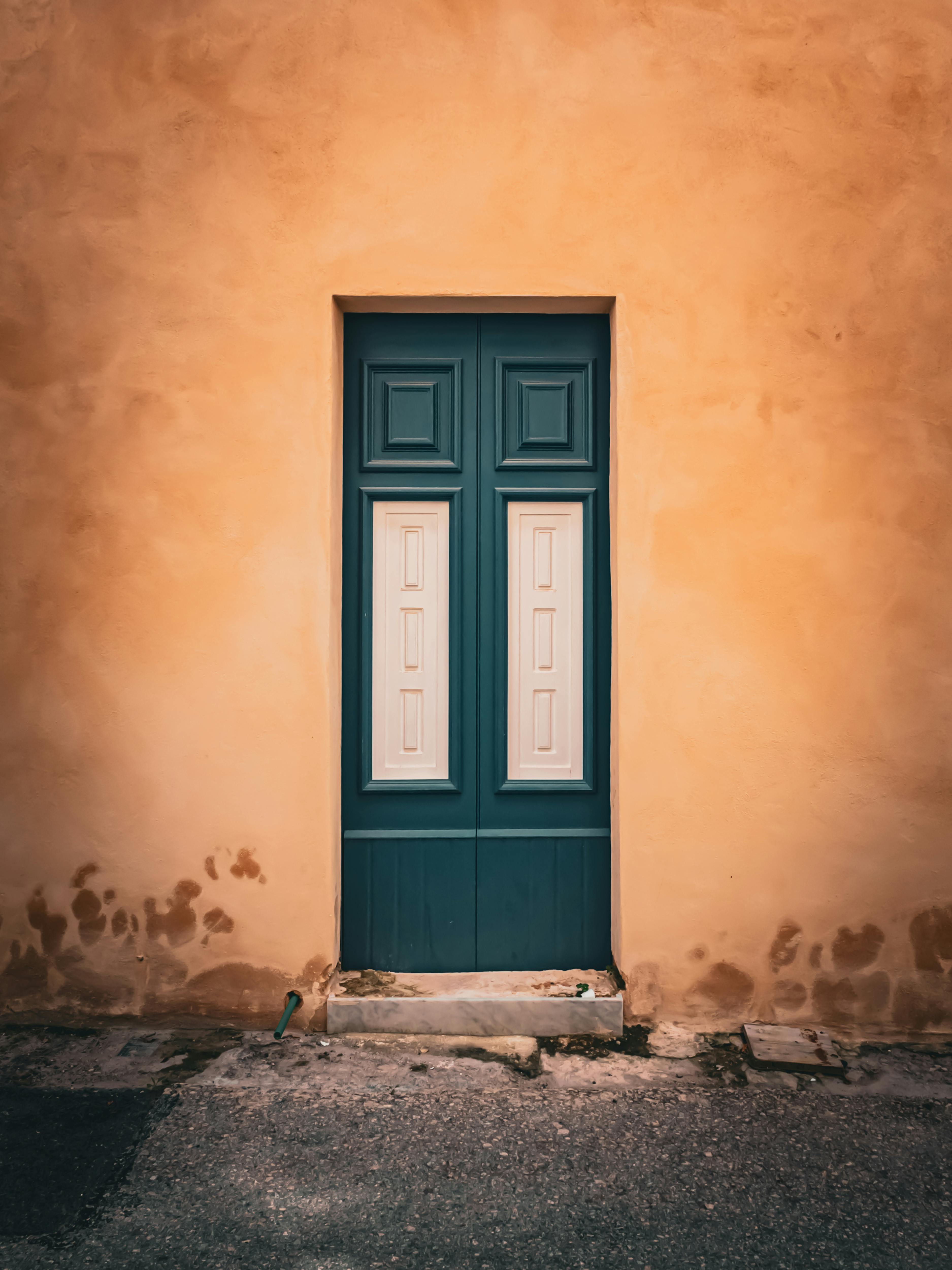 免费 一扇复古的木门镶嵌在纹理丰富的赭色墙壁上，完美地体现了乡村魅力和建筑优雅。 素材图片