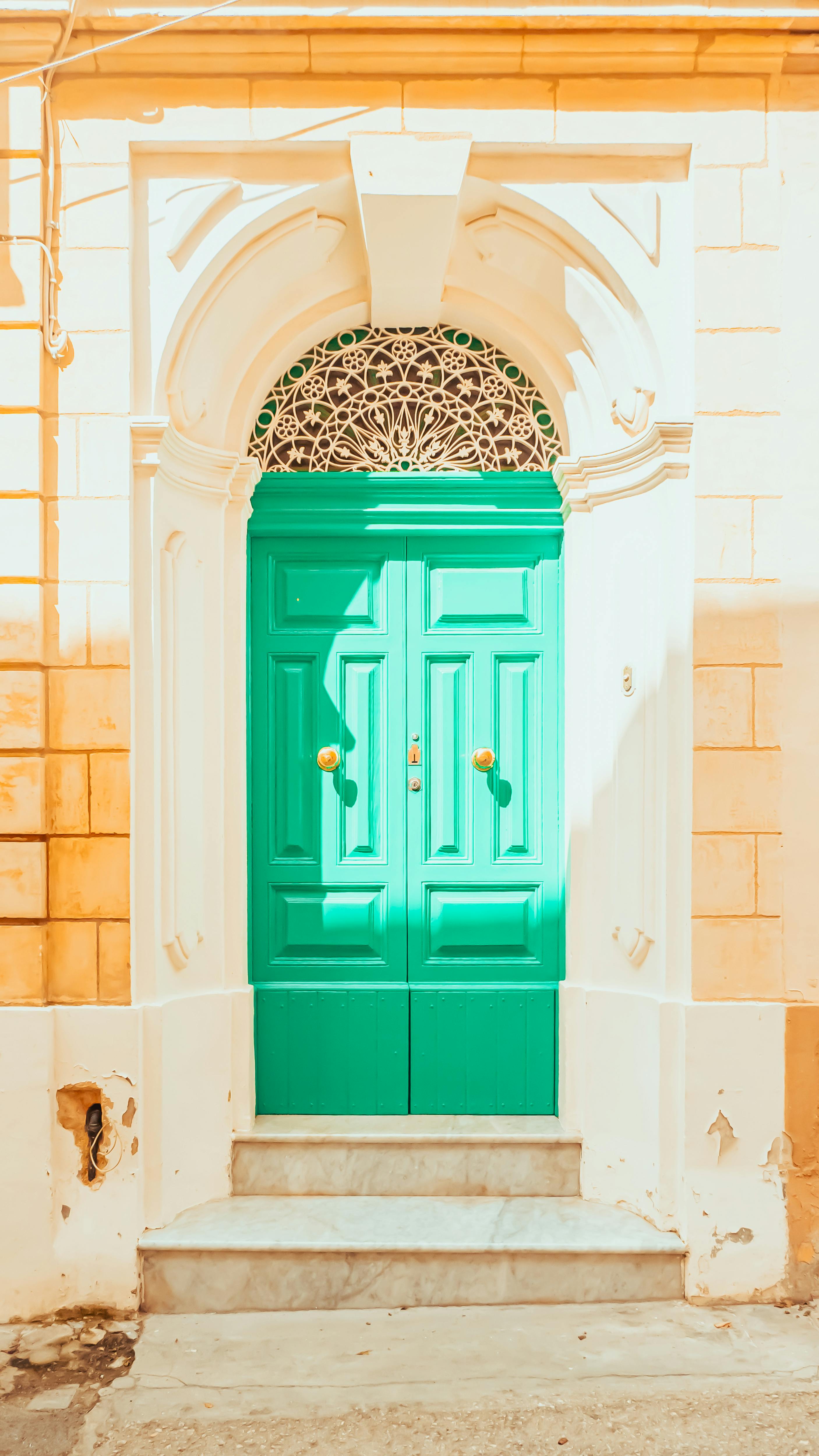 Zadarmo Jasne zelené dvere zasadené do slnkom zaliatej architektonickej fasády s ozdobným dizajnom. Fotka z fotobanky
