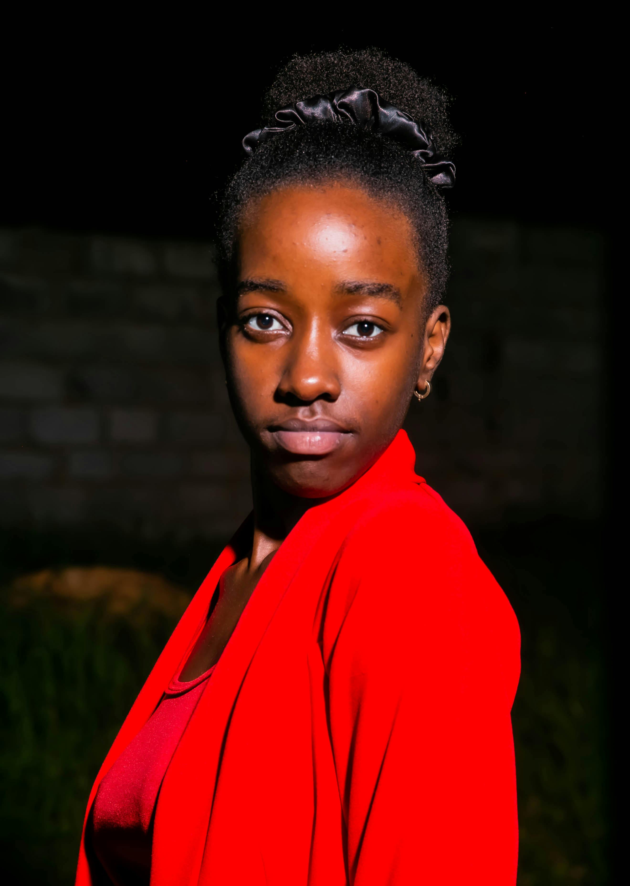 무료 어두운 배경을 뒤로하고 강렬한 빨간색 재킷을 입은 여성의 인상적인 초상화로, 우아함과 자신감을 강조합니다. 스톡 사진