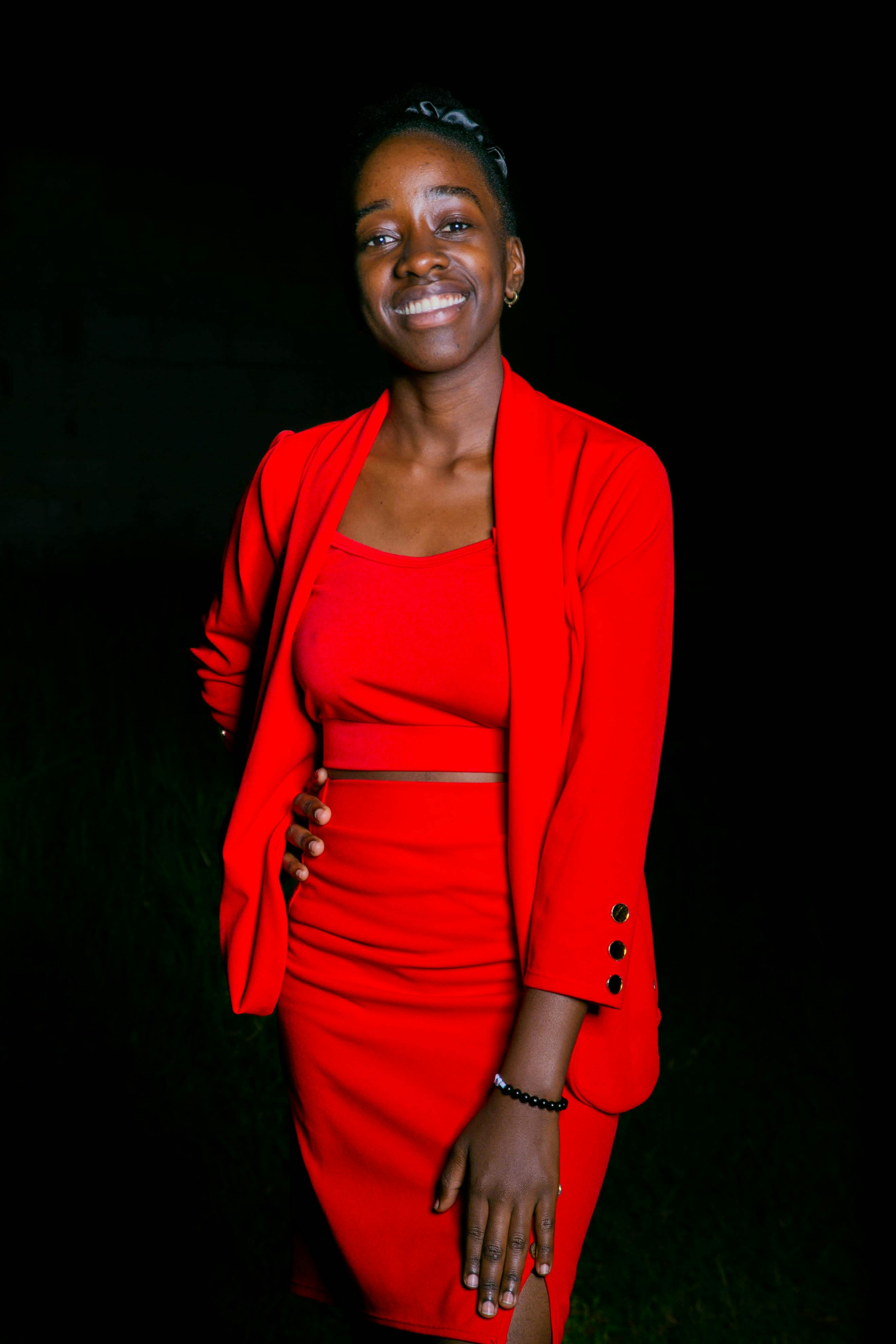 Miễn phí Người phụ nữ tươi cười trong bộ trang phục màu đỏ nổi bật tạo dáng trước phông nền tối, toát lên vẻ tự tin và phong cách. Ảnh lưu trữ