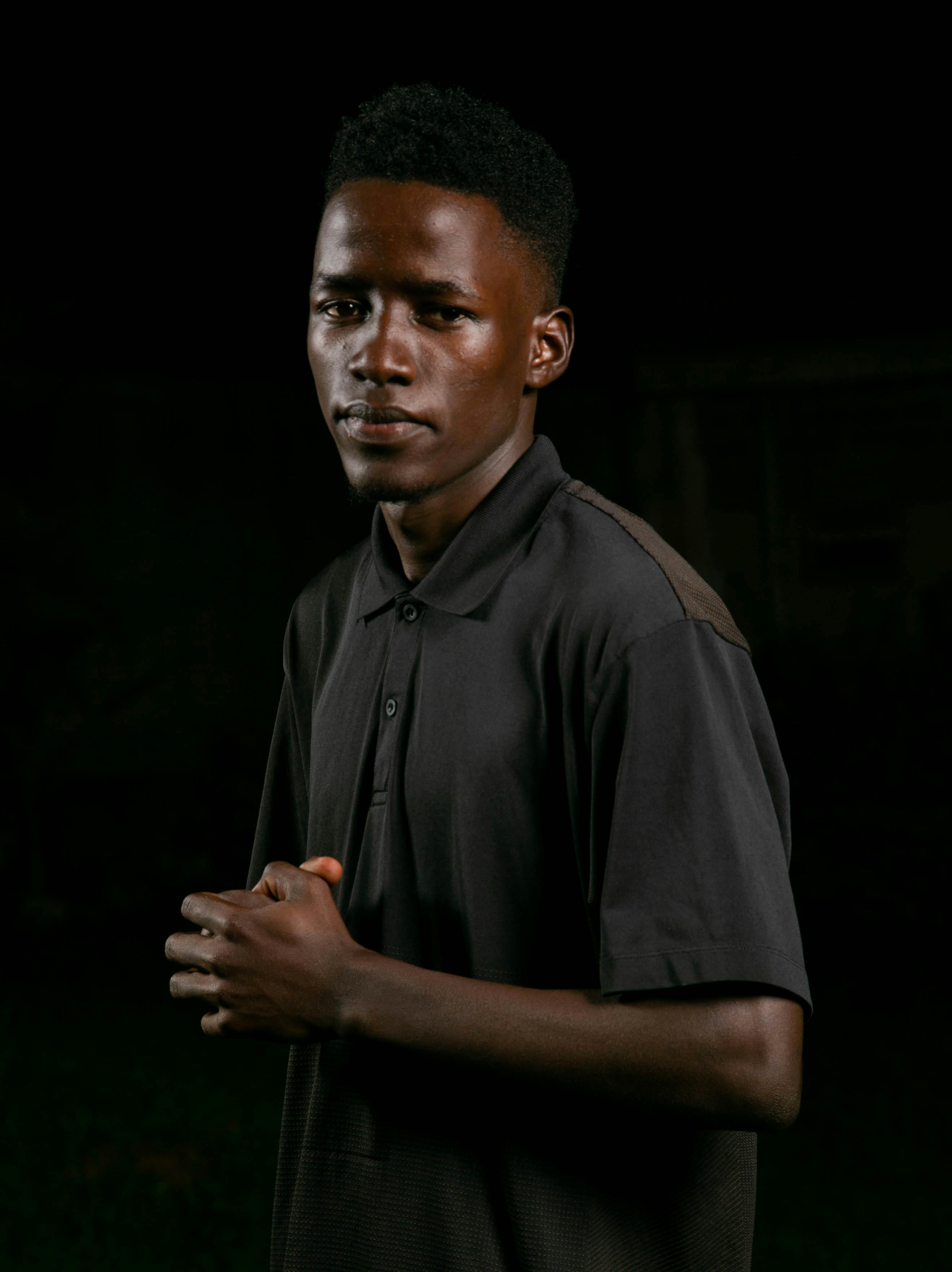 bezplatná Podmanivý portrét mladého muže sebevědomě stojícího na tmavém pozadí. Základová fotografie