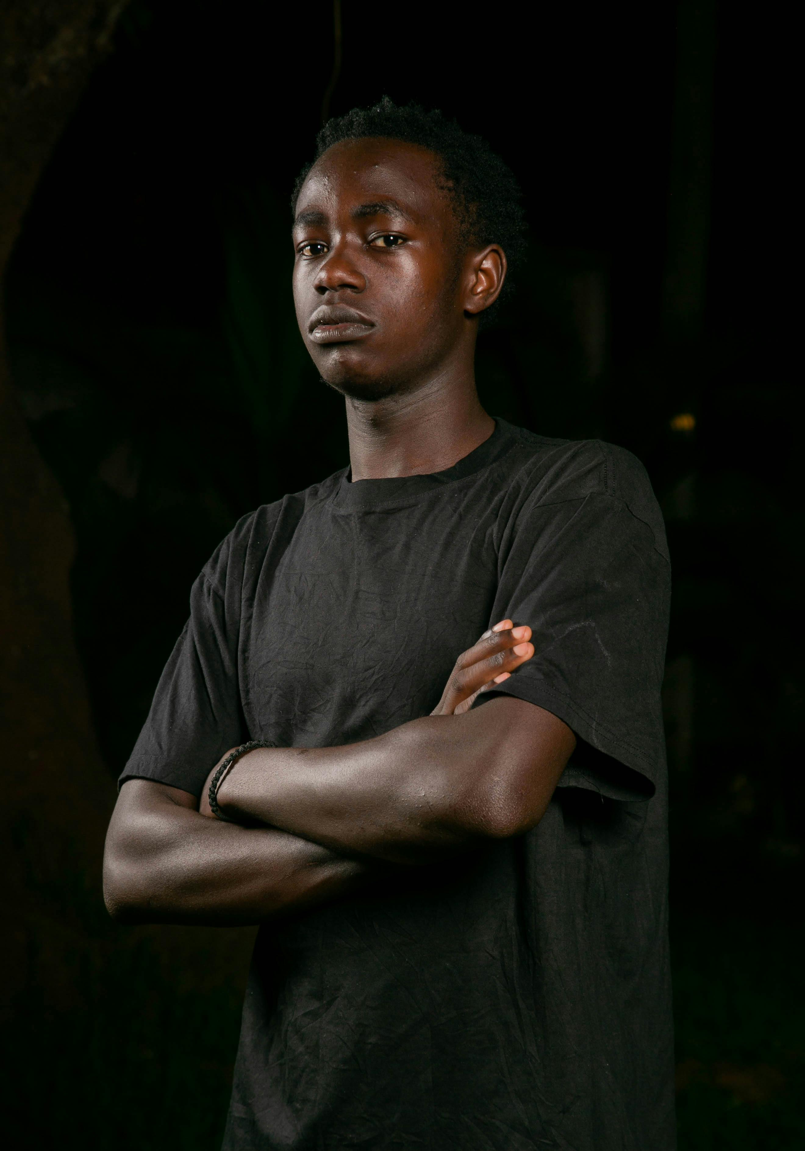 Portrait of a confident young man standing with arms crossed, outdoors at night.